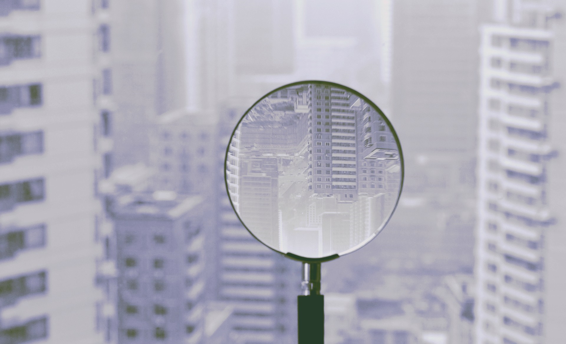 Magnifying glass over city buildings HD Wallpaper