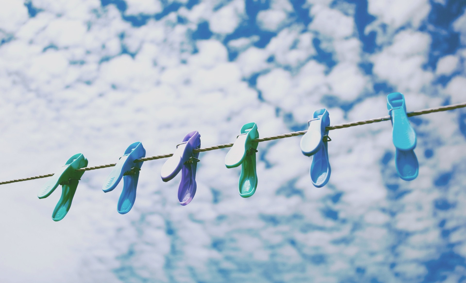 Colorful clothespins on a clothesline against a cloudy sky HD Wallpaper