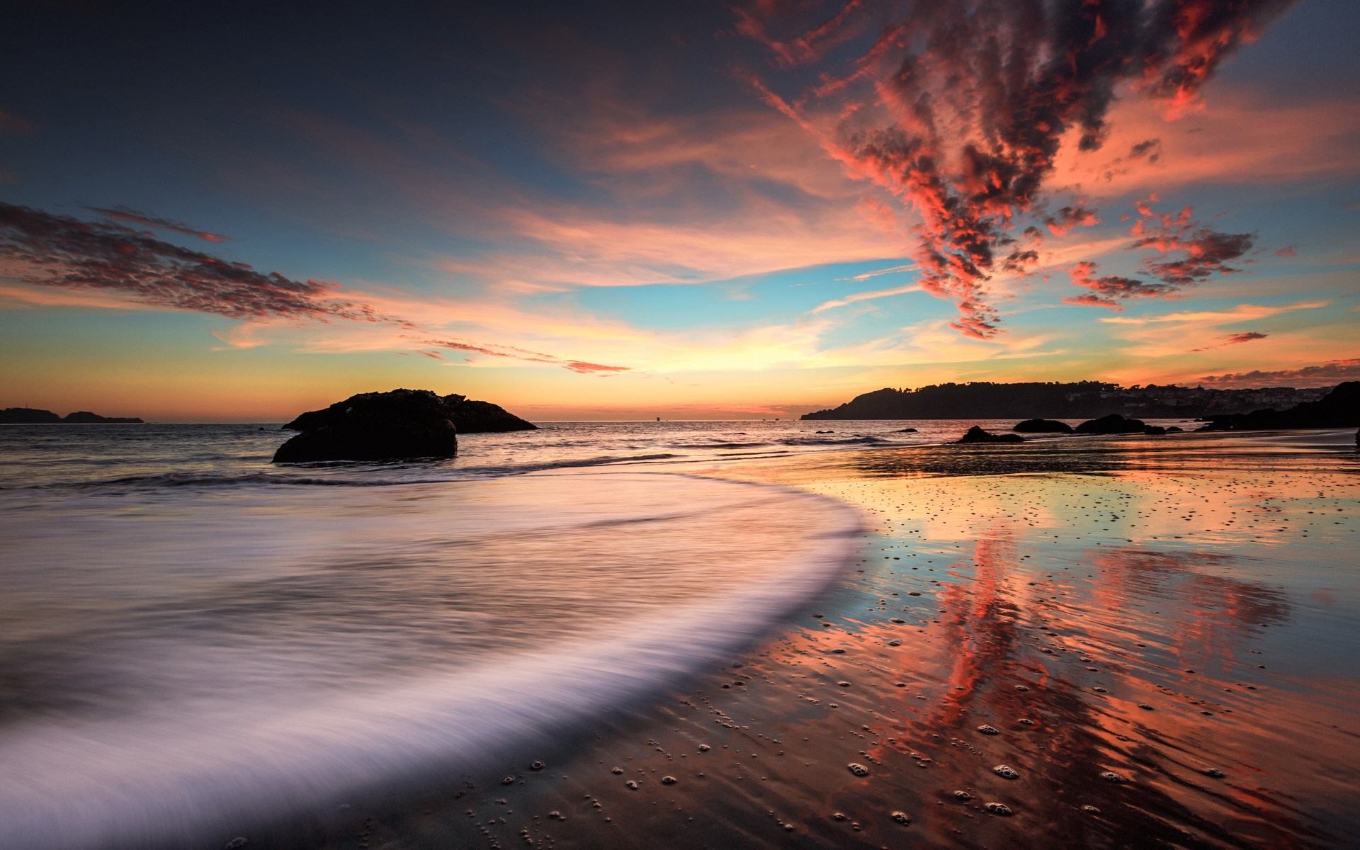 Sunset over a rocky beach with colorful clouds HD Wallpaper