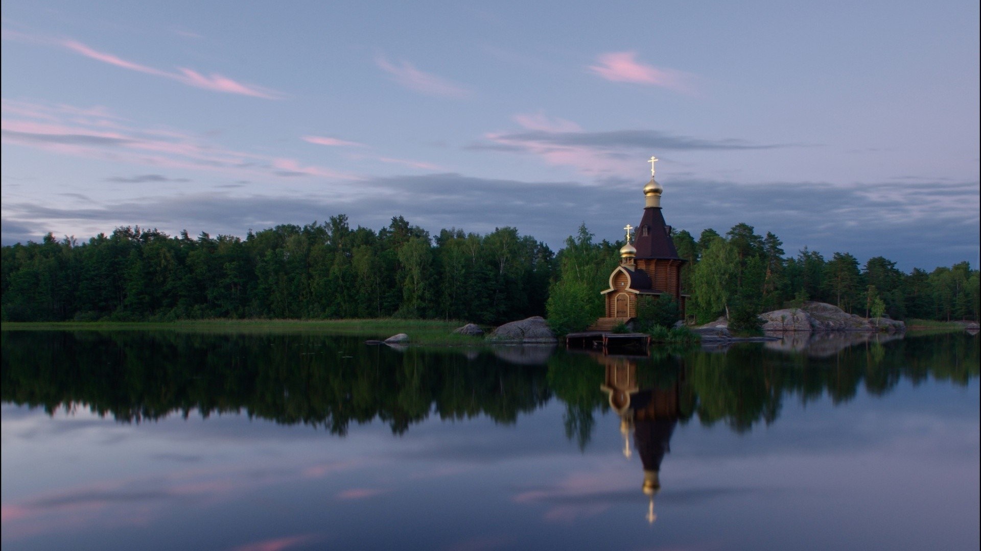 Wooden church with golden domes reflected in a calm lake at dusk HD Wallpaper