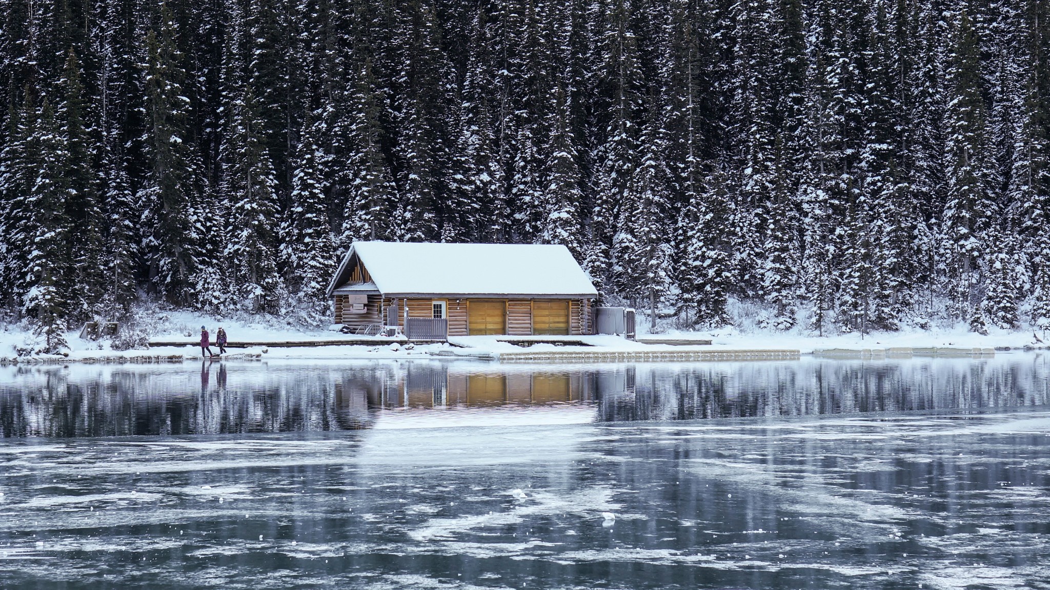Wooden cabin by a frozen lake with snow-covered trees HD Wallpaper