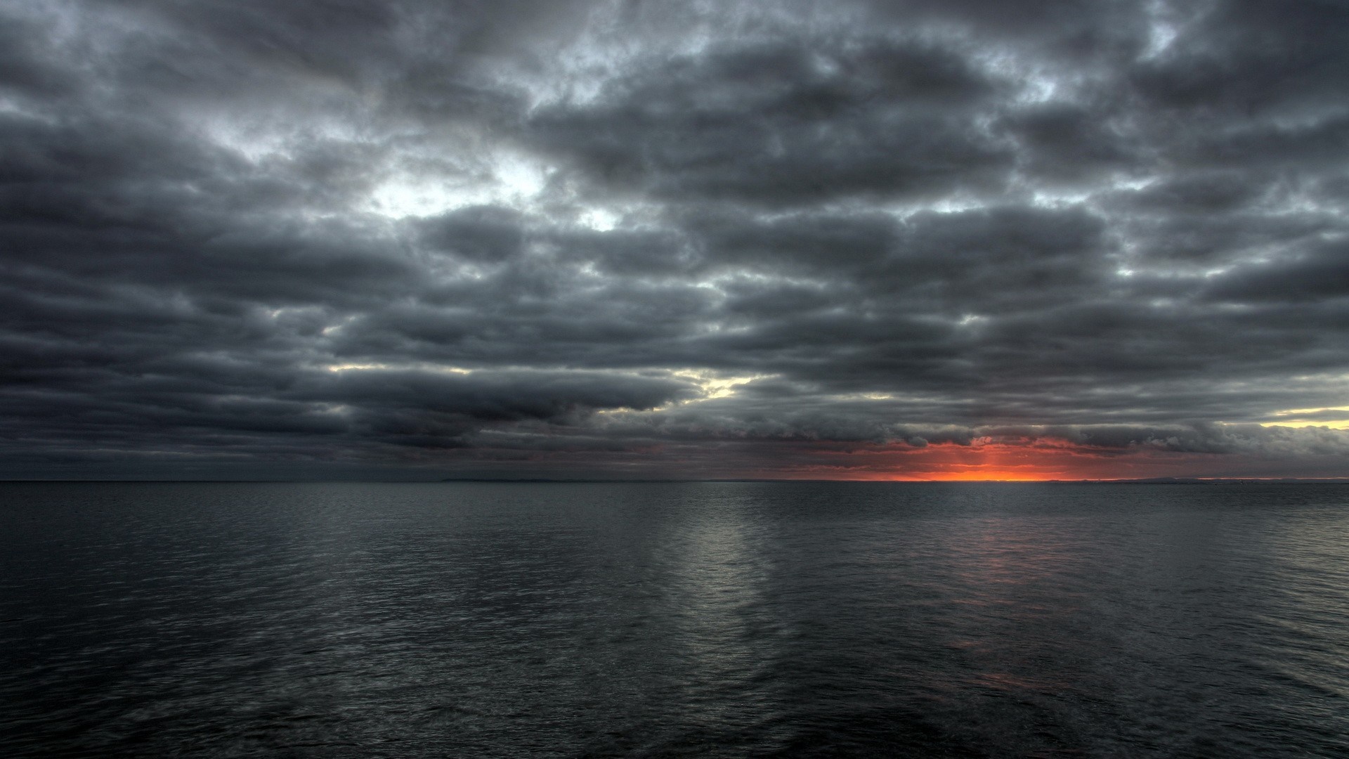 Sunset over the ocean with dark clouds HD Wallpaper