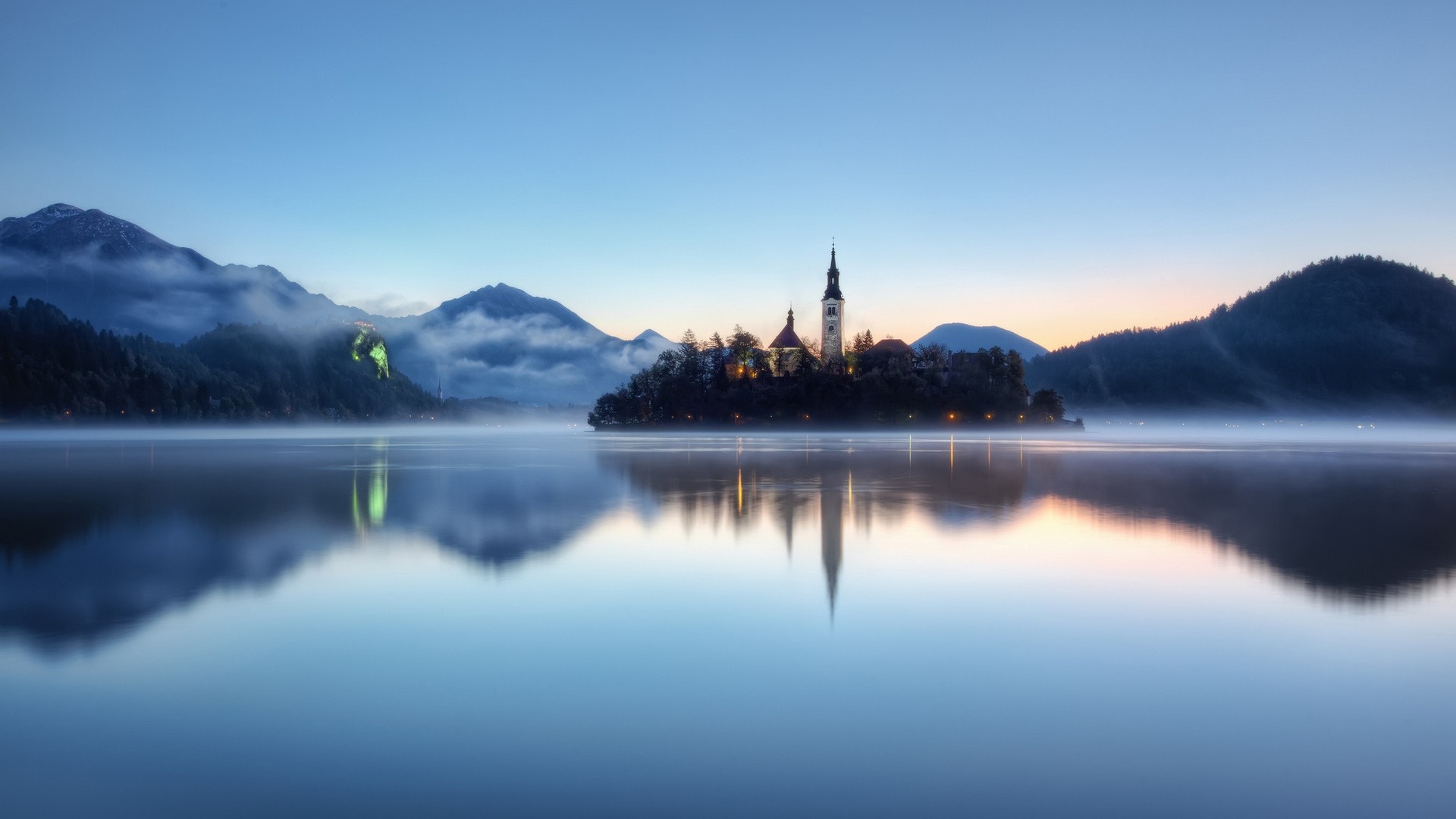 Island church in lake at dawn with misty mountains HD Wallpaper