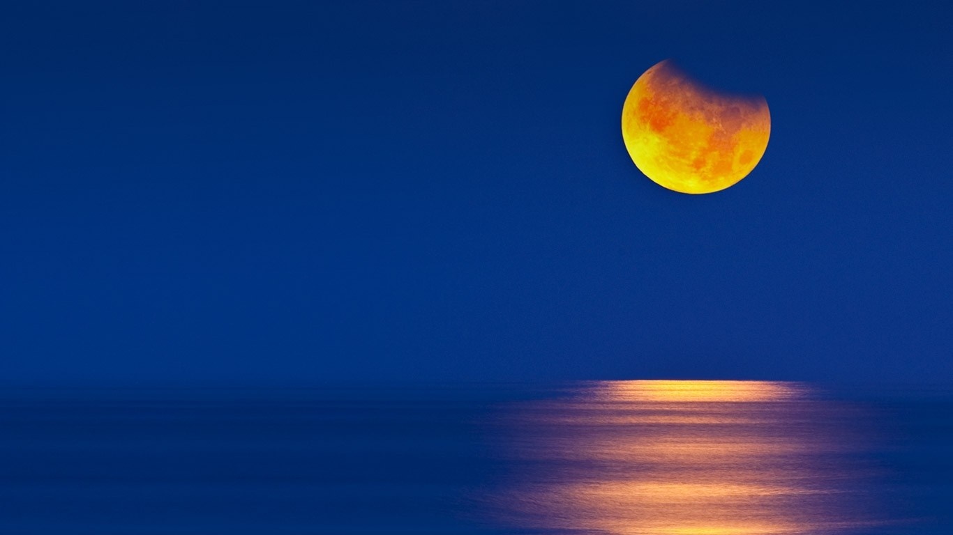 Partial lunar eclipse over the ocean at night HD Wallpaper