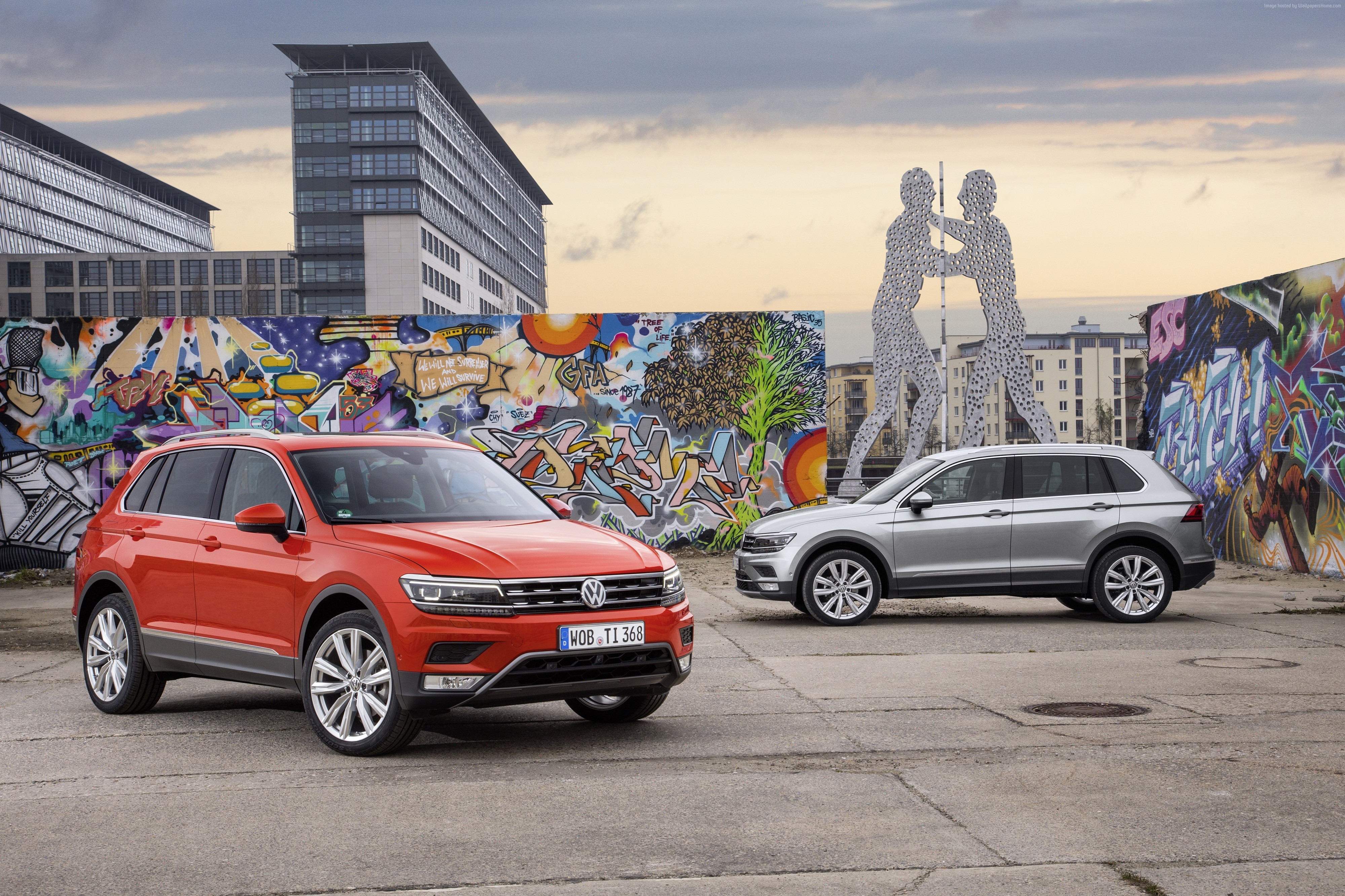 Orange and grey Volkswagen Tiguan SUVs parked near graffiti wall HD Wallpaper