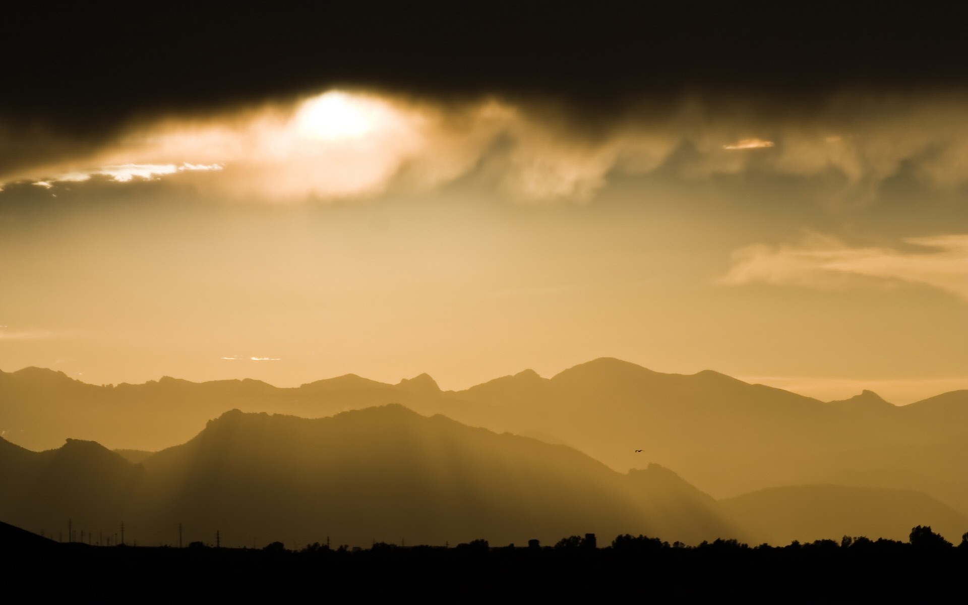 Sunlight filtering through clouds over mountain ranges at sunset HD Wallpaper