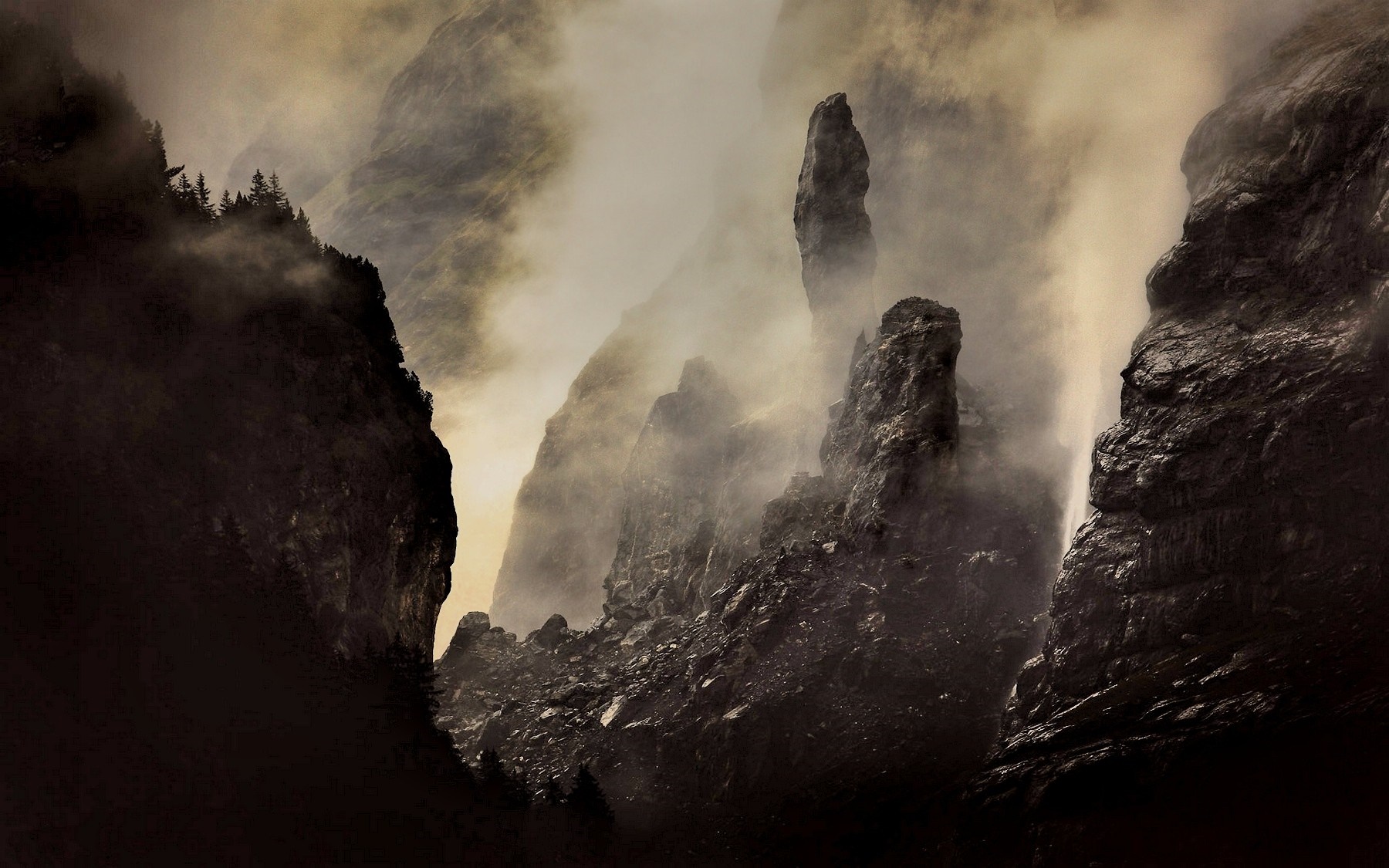 Misty mountain peaks with dark rocks and forest HD Wallpaper