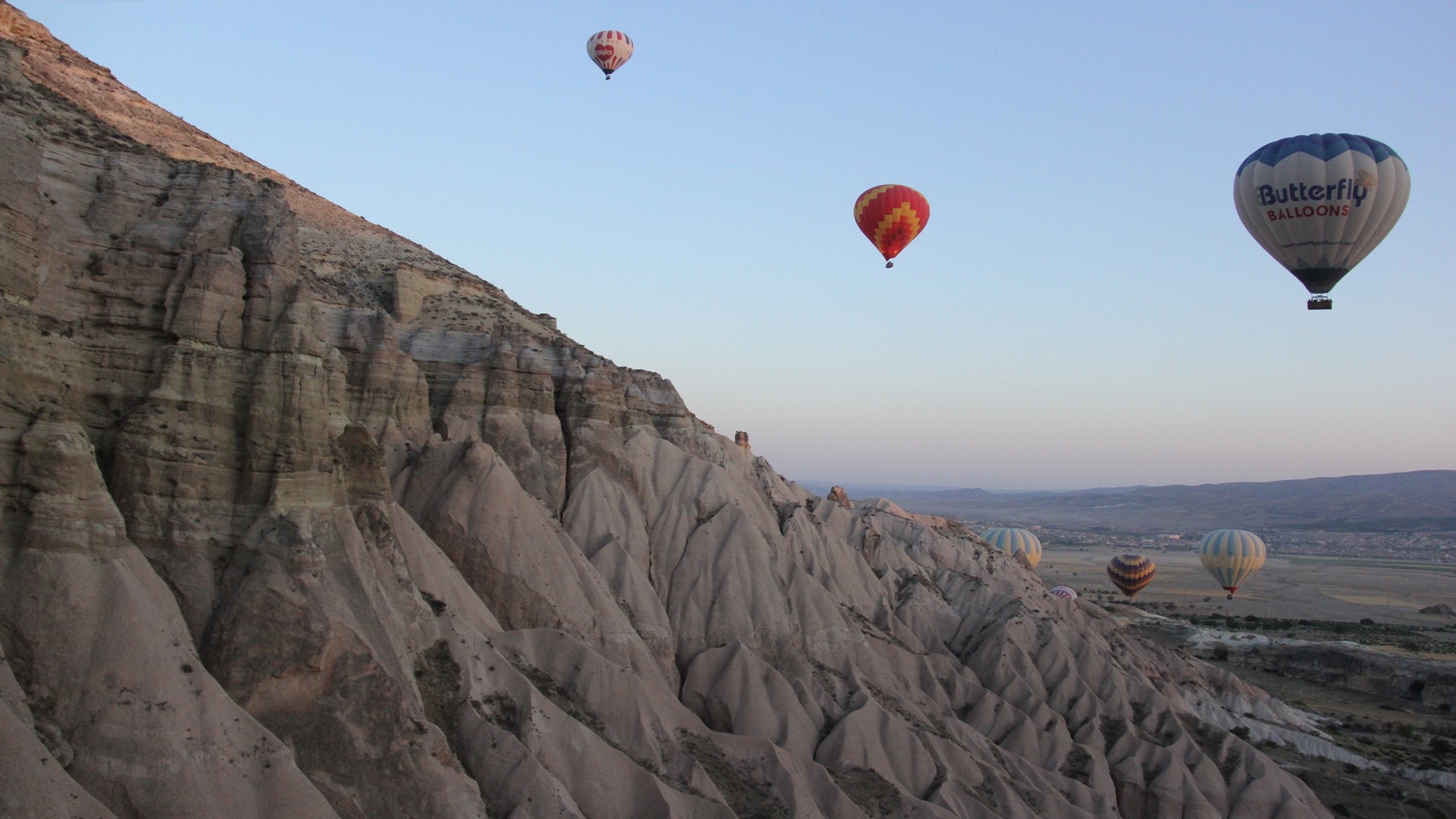 Hot air balloons flying over rocky landscape HD Wallpaper