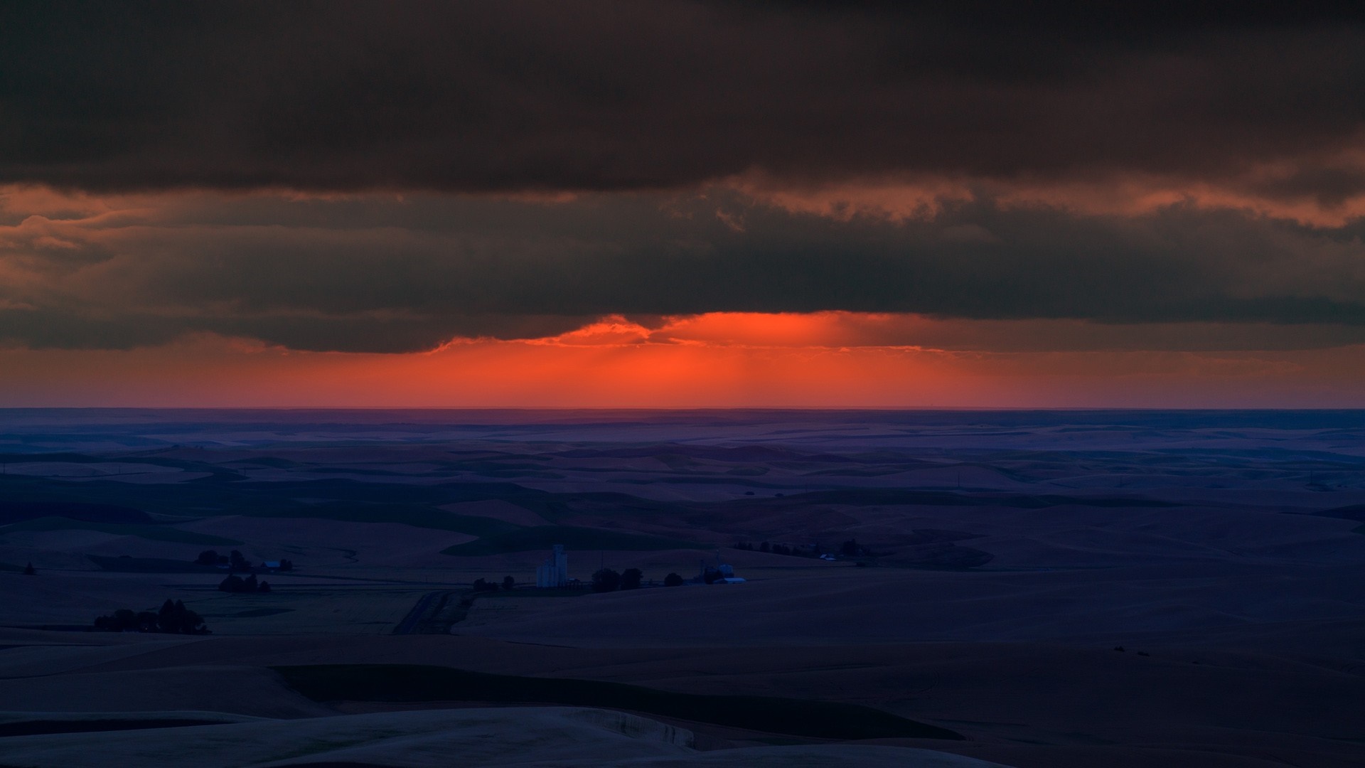 Sunset over rolling hills with dark clouds HD Wallpaper