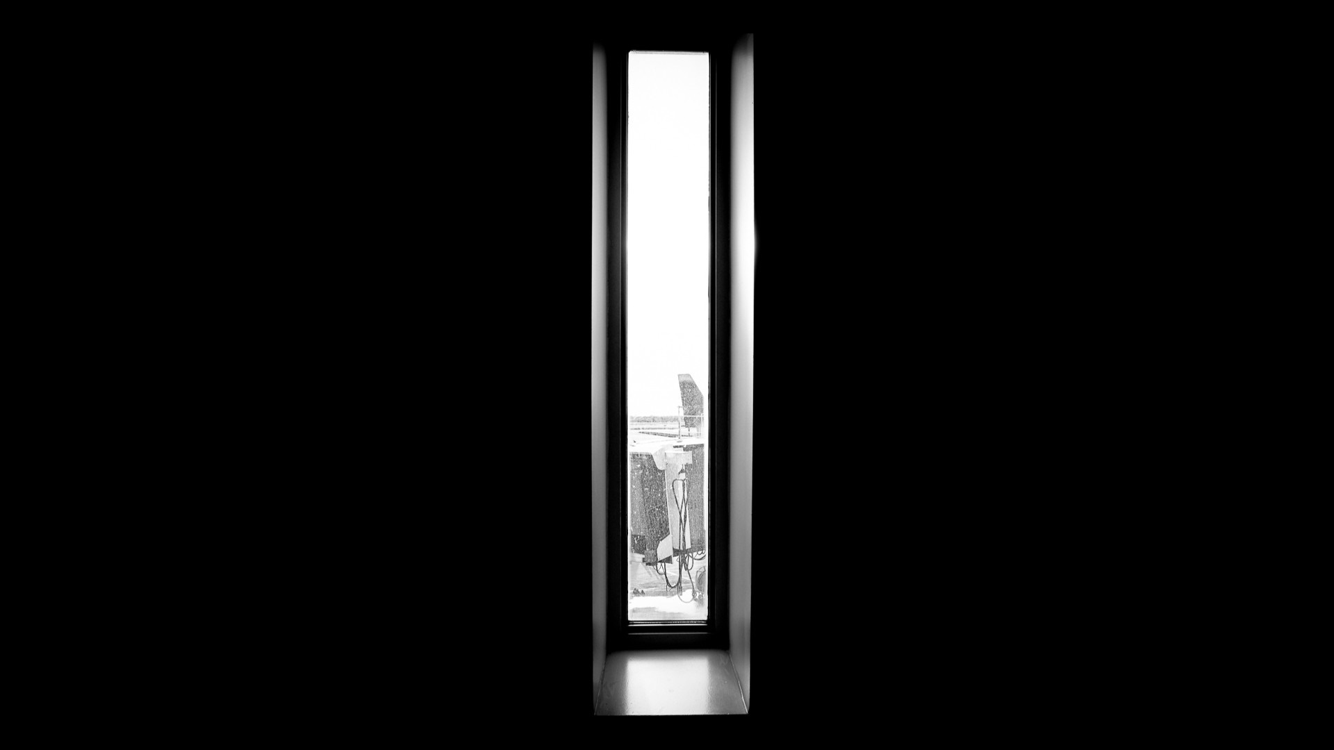 Tall narrow window overlooking an airport tarmac HD Wallpaper