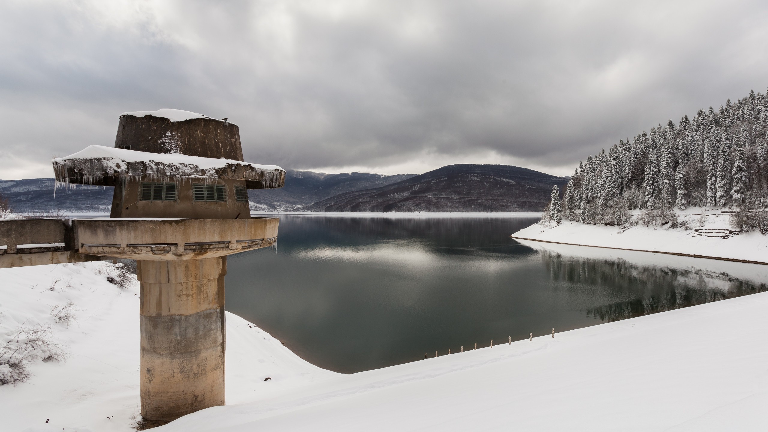 Concrete tower by a snow-covered lake in winter HD Wallpaper