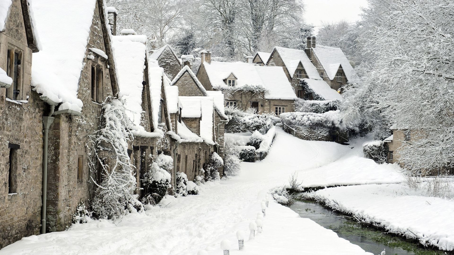 Snowy cottages along a stream in Bibury, England HD Wallpaper