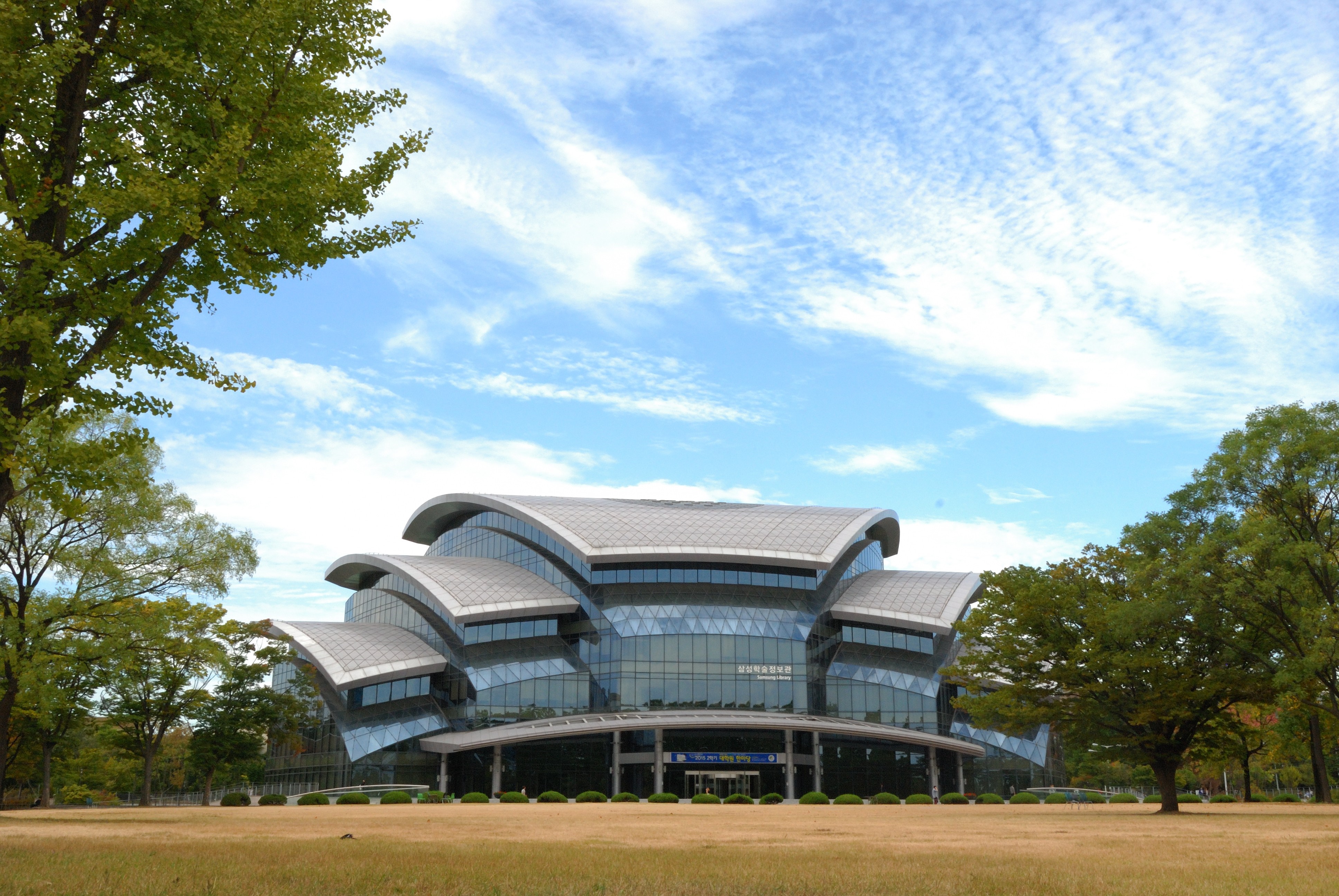 Modern building with curved roof and glass facade in a park HD Wallpaper