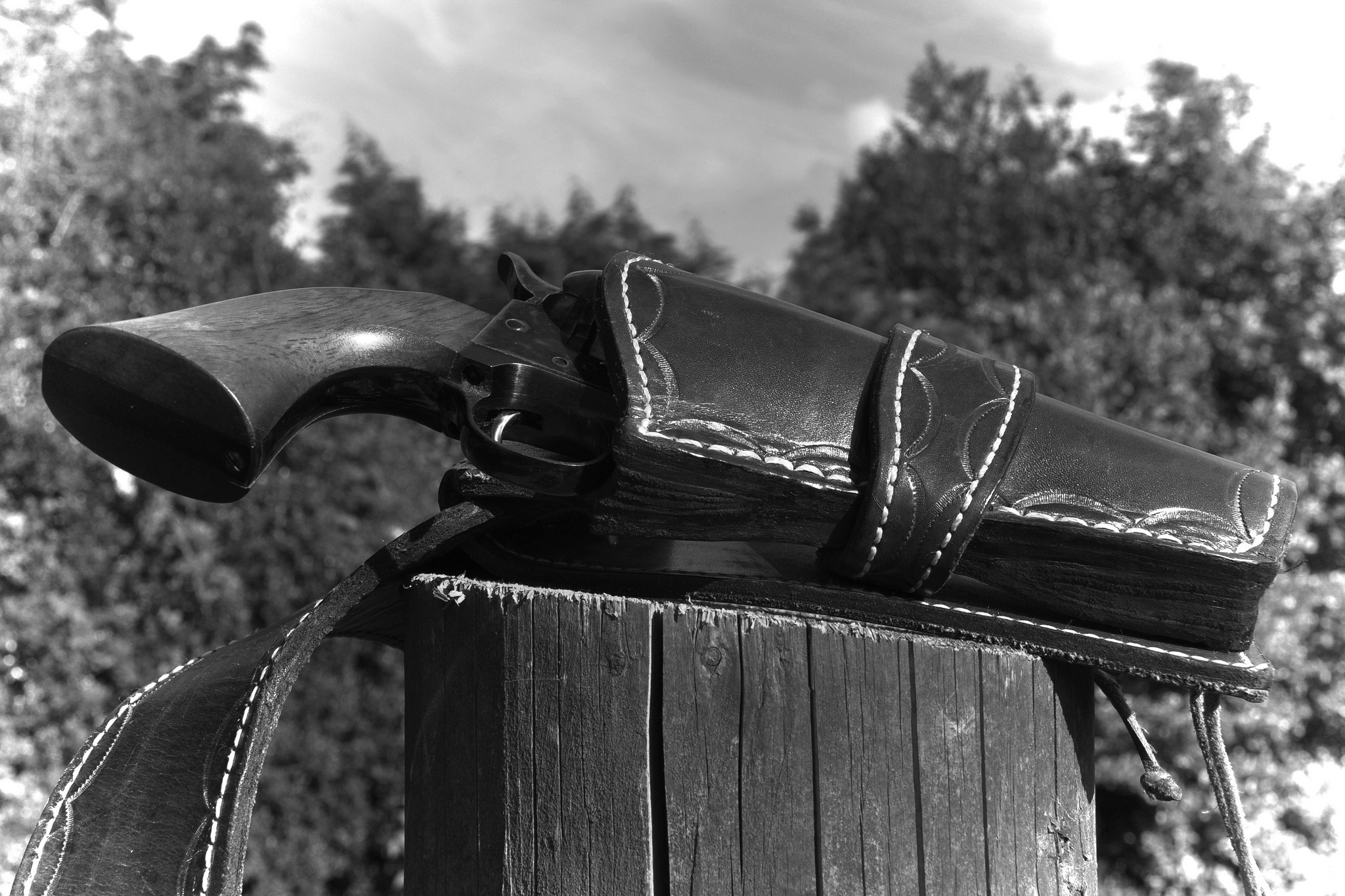 Revolver in a leather holster on a wooden post HD Wallpaper