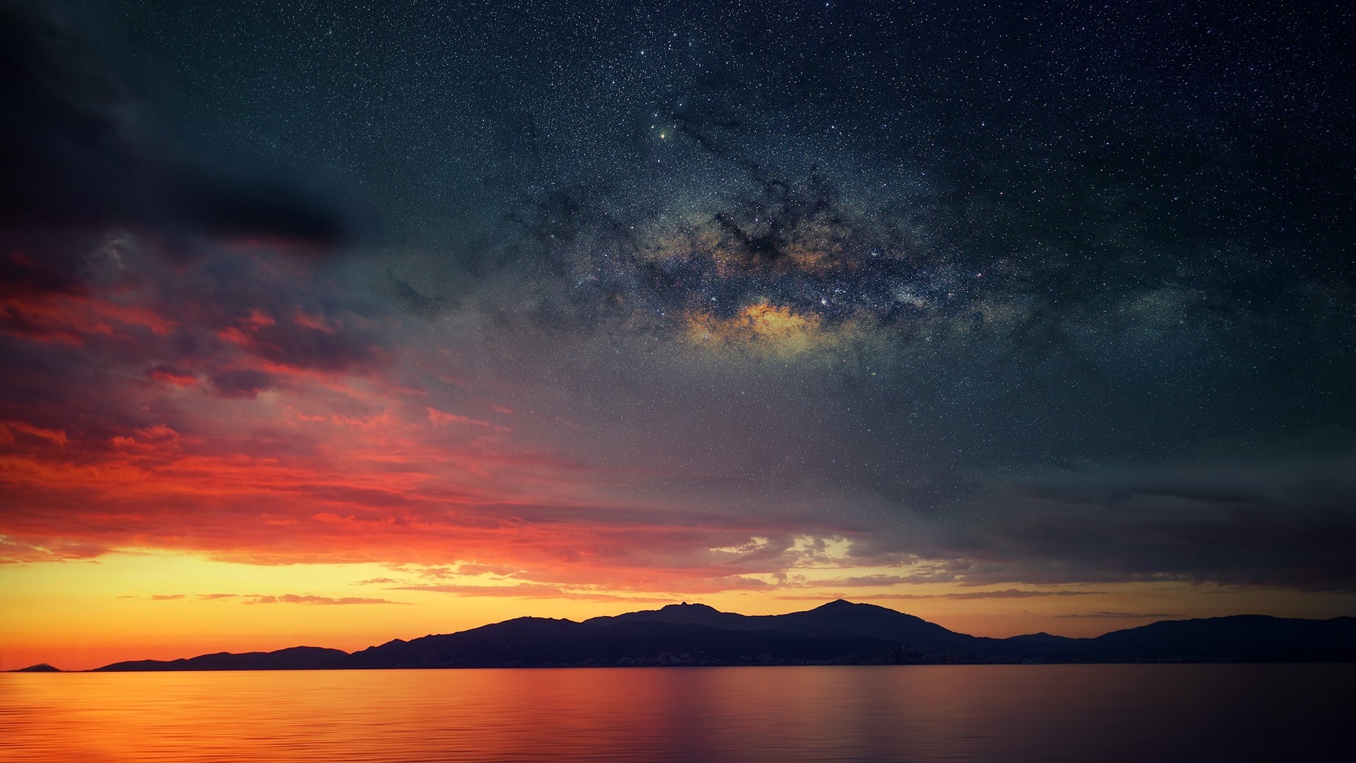 Milky Way over a sunset horizon with mountains and sea HD Wallpaper
