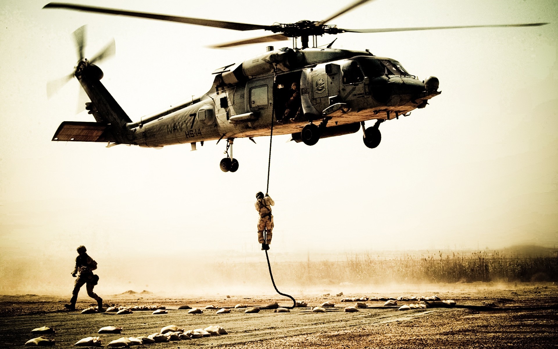 US Navy helicopter performing a rope descent in a desert HD Wallpaper