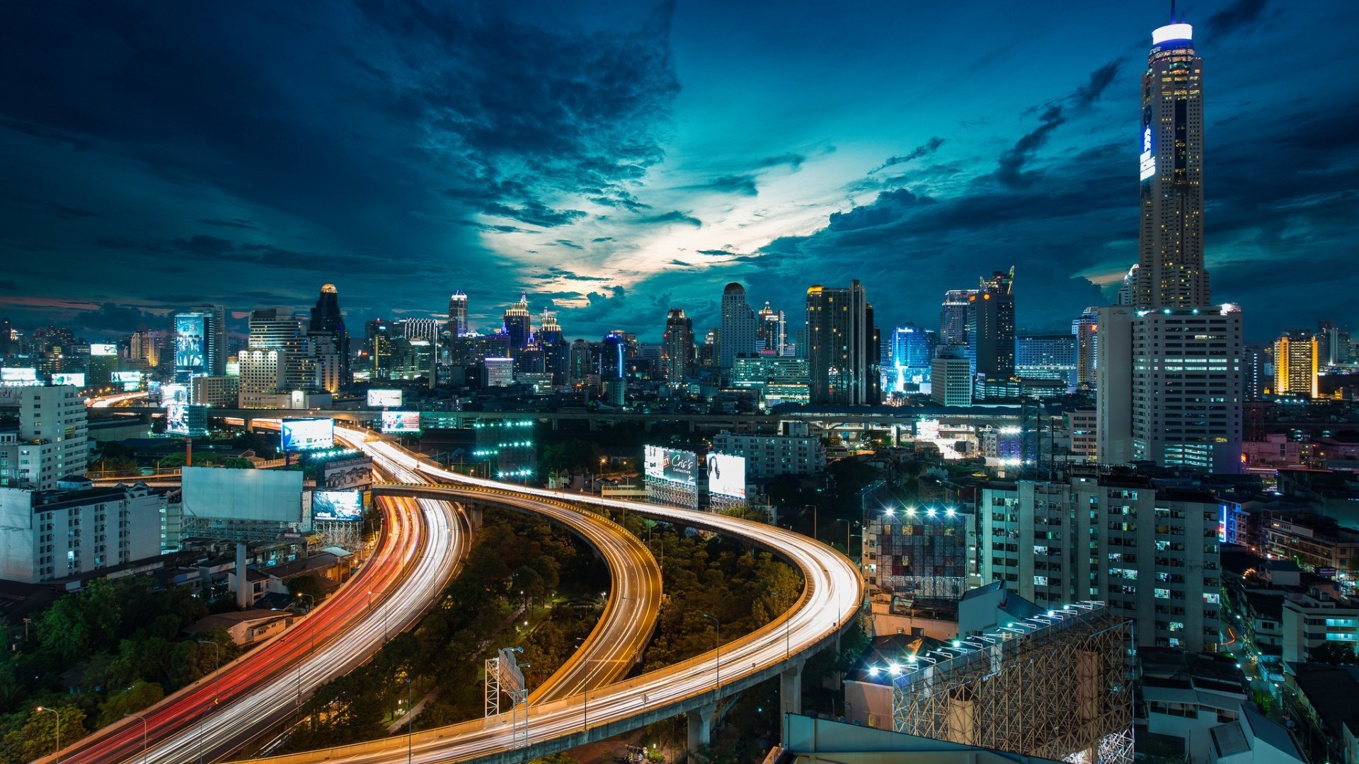 Cityscape at night with light trails on highways HD Wallpaper