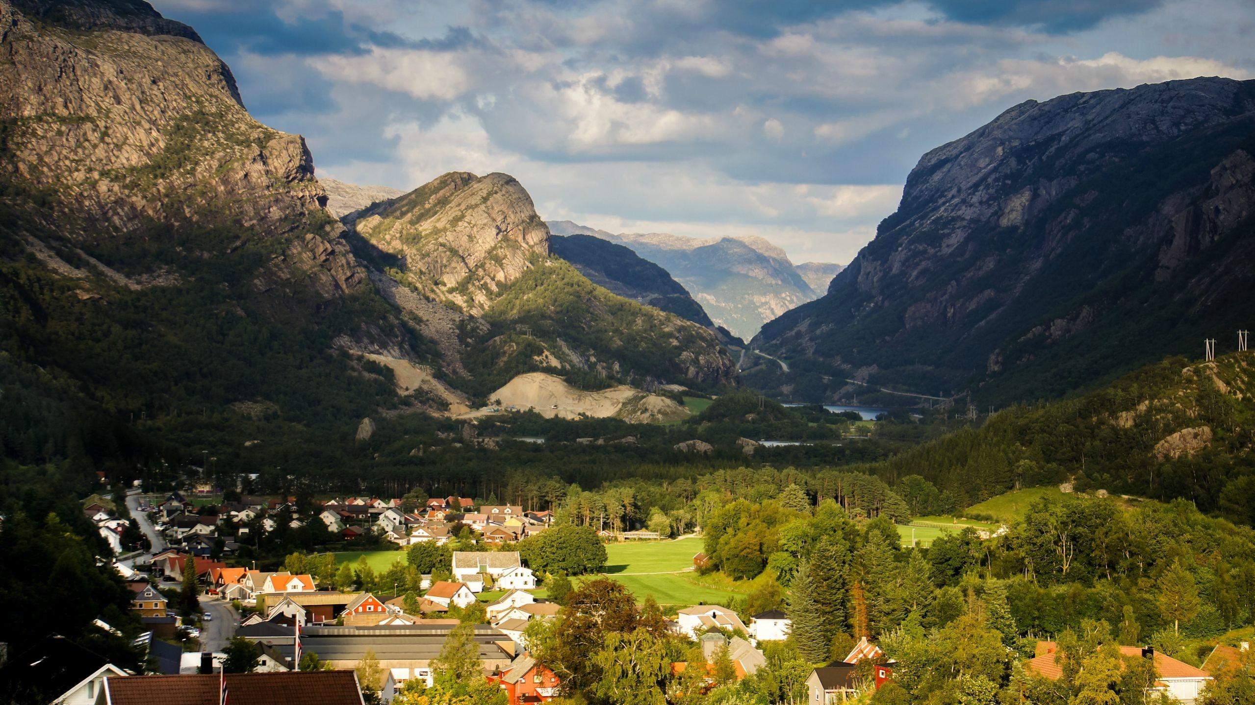Village nestled in a Norwegian valley with mountains HD Wallpaper