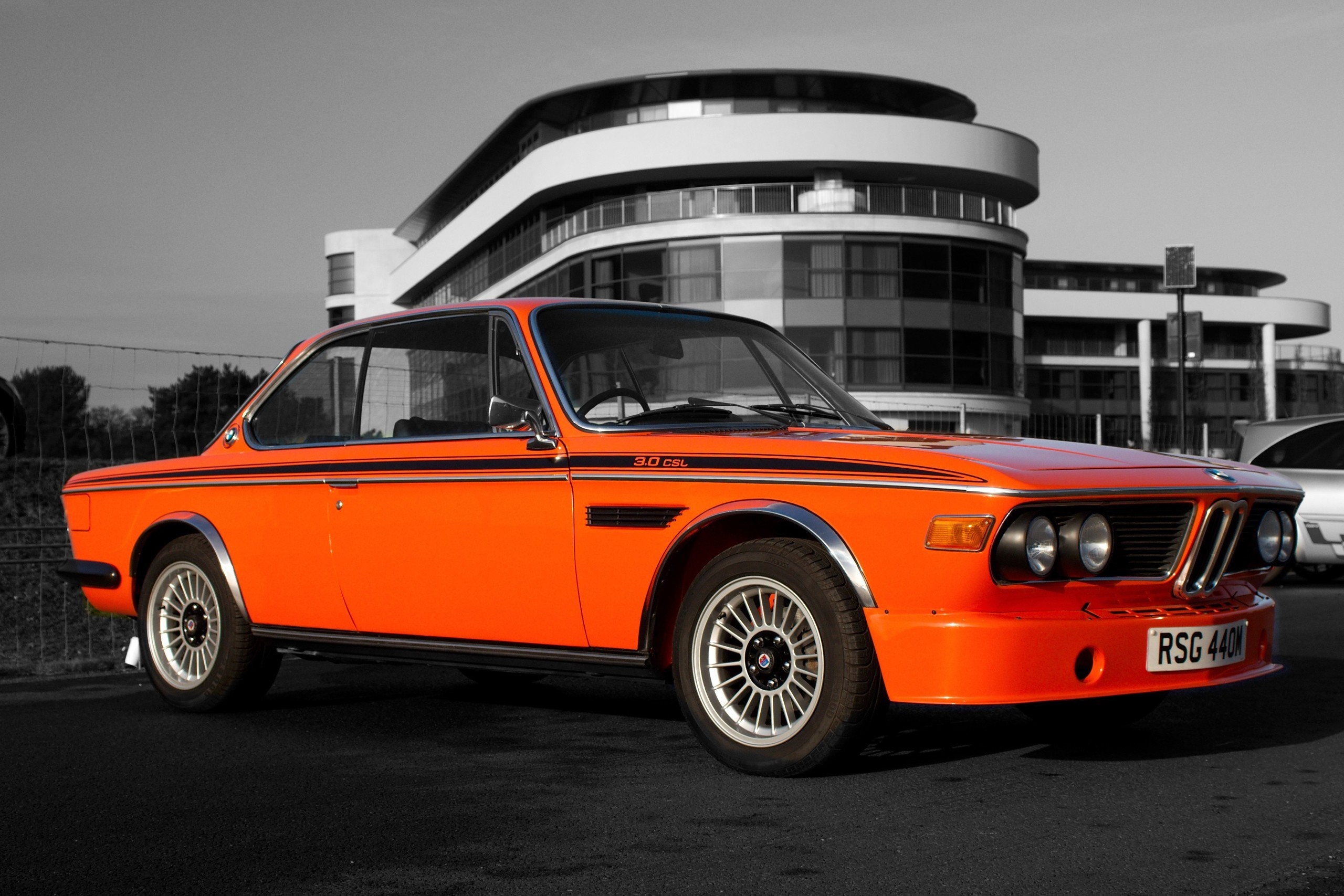 Orange BMW 3.0 CSL Coupe in front of a modern building HD Wallpaper