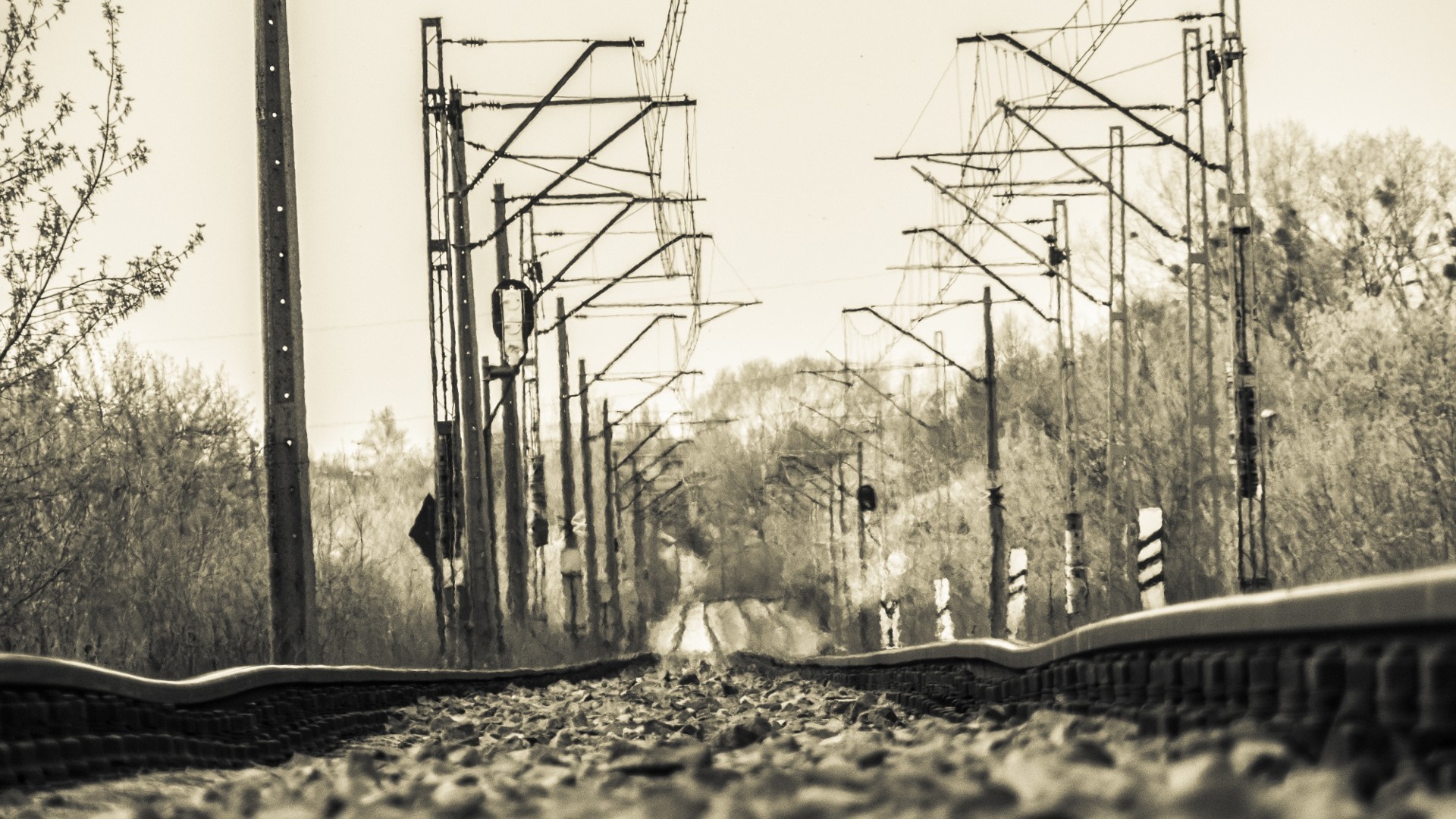 Monochrome railway tracks with overhead power lines HD Wallpaper