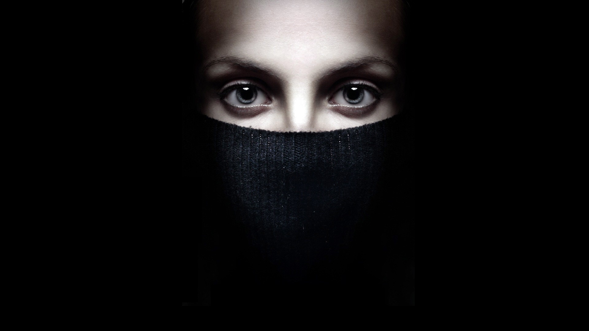 Close up of a woman's eyes and mouth covered by a black sweater HD Wallpaper