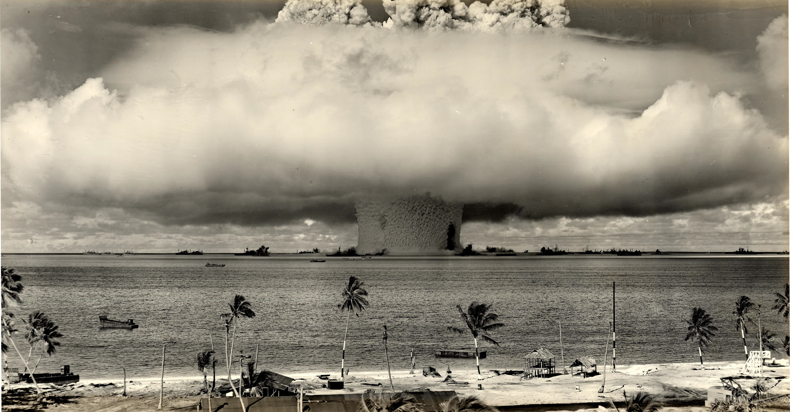 Nuclear explosion over the ocean with ships and palm trees HD Wallpaper