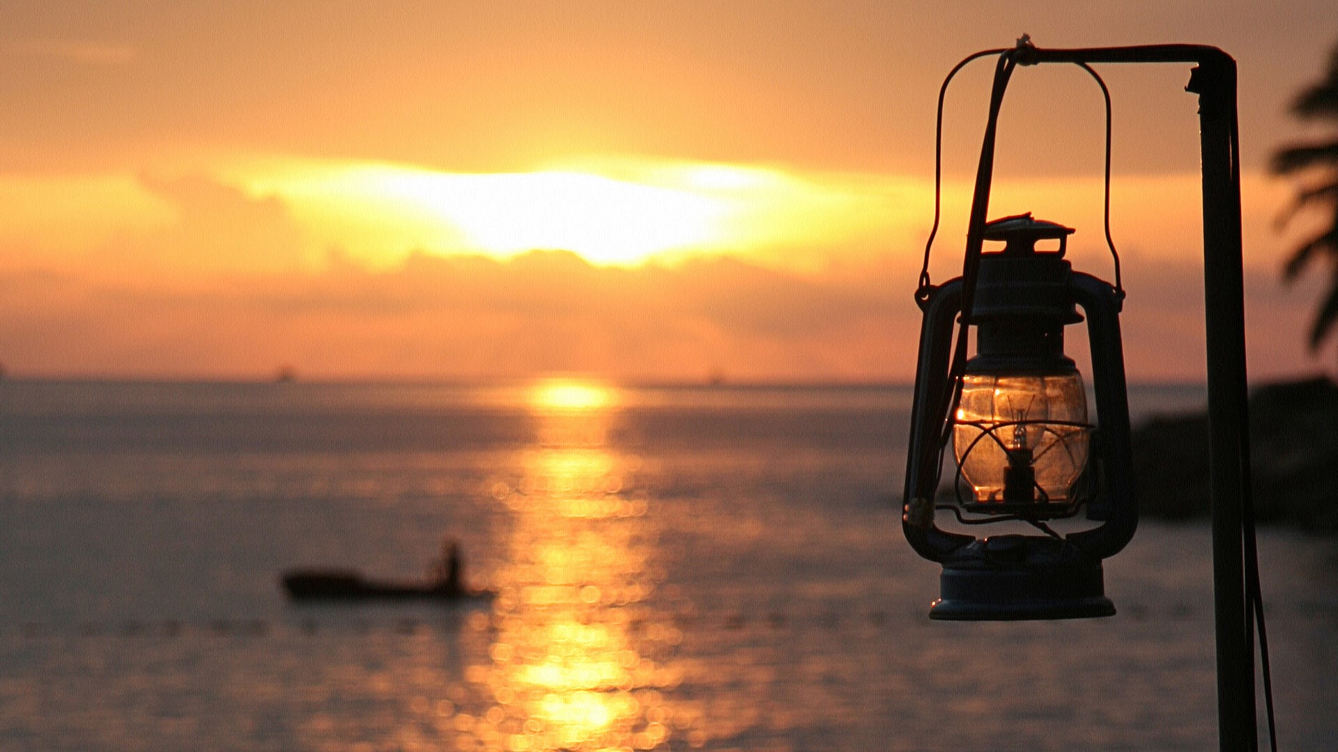 Lantern at sunset over the ocean with a boat HD Wallpaper