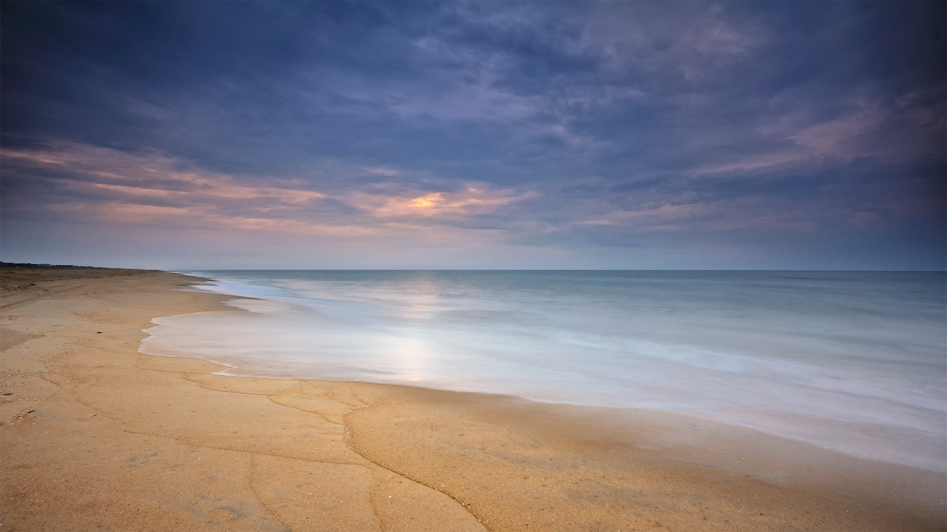 Beach at sunset with ocean waves and clouds HD Wallpaper