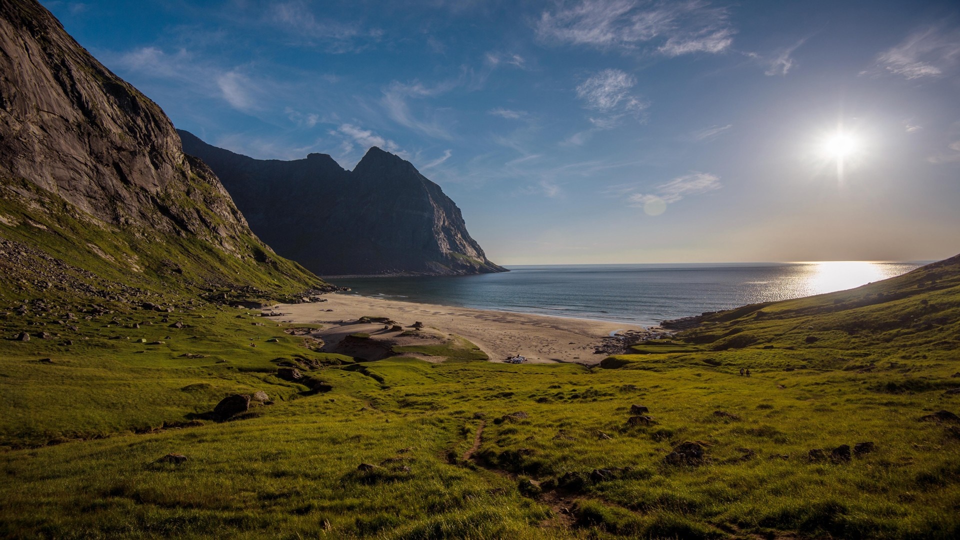 Mountainous coast with a beach and ocean under a sunny sky HD Wallpaper