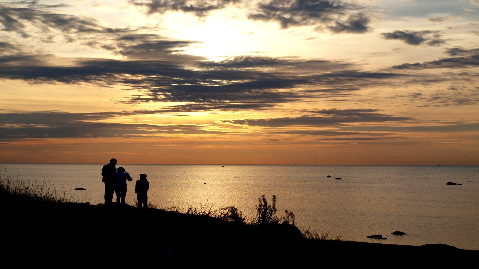 Silhouettes of people watching the sunset over the sea HD Wallpaper