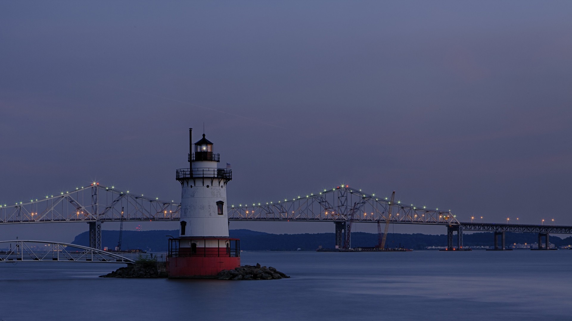 Lighthouse and bridge over water at dusk HD Wallpaper