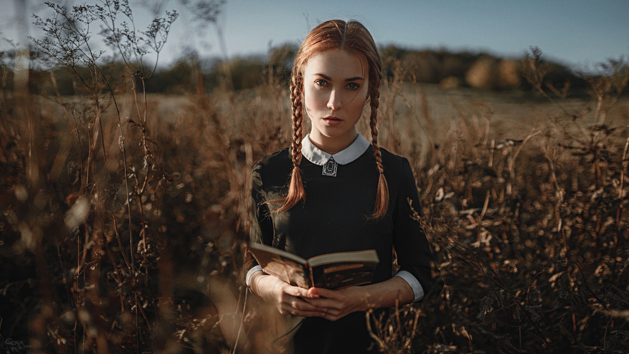 Woman with braids holding a book in a field HD Wallpaper
