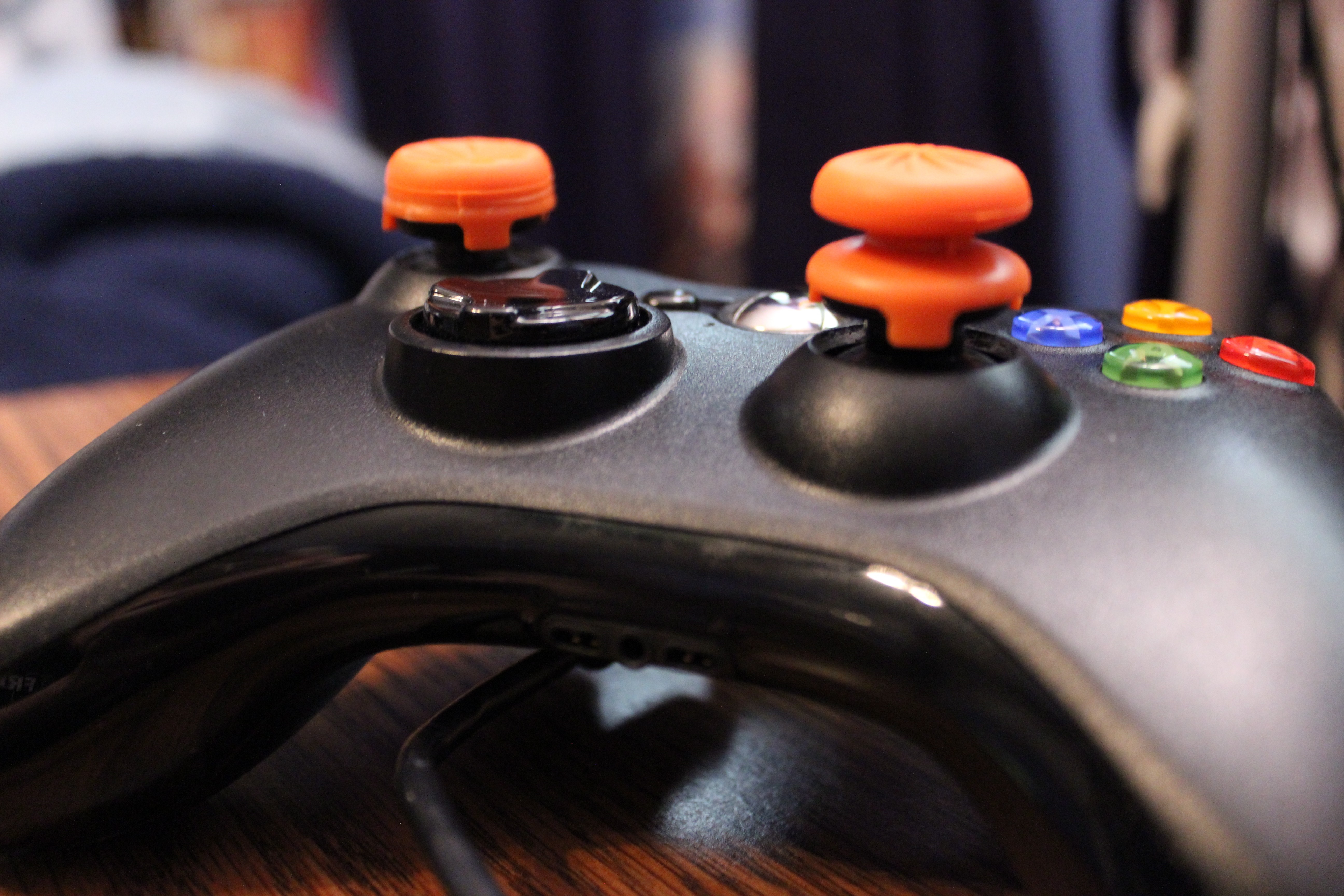 Close-up of an Xbox 360 controller with orange joystick covers HD Wallpaper
