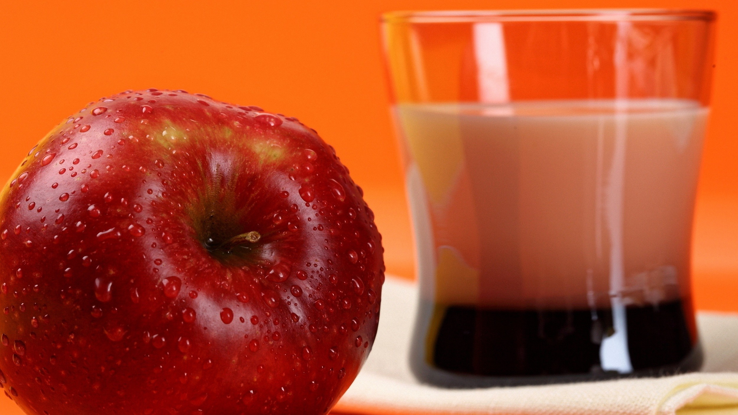 Red apple and glass of juice on orange background HD Wallpaper