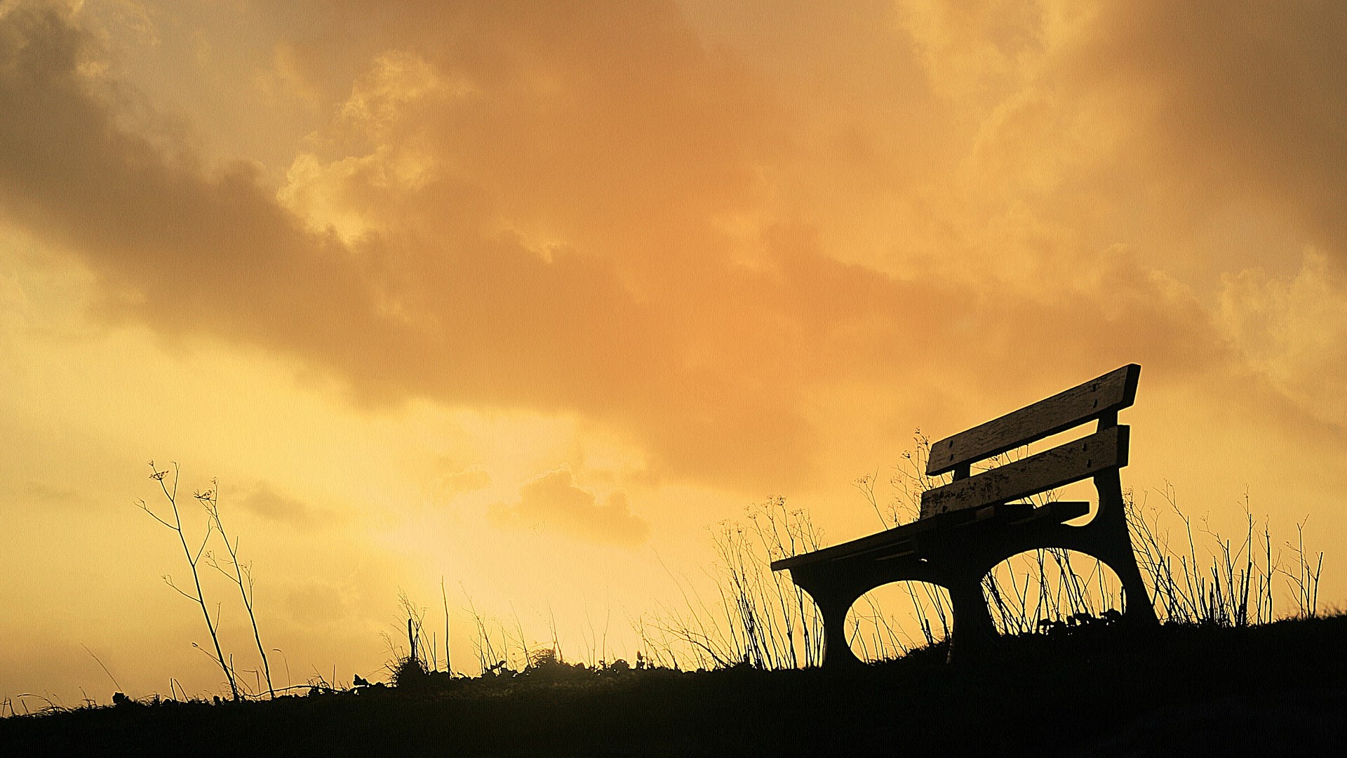 Silhouette of a park bench against a sunset sky HD Wallpaper
