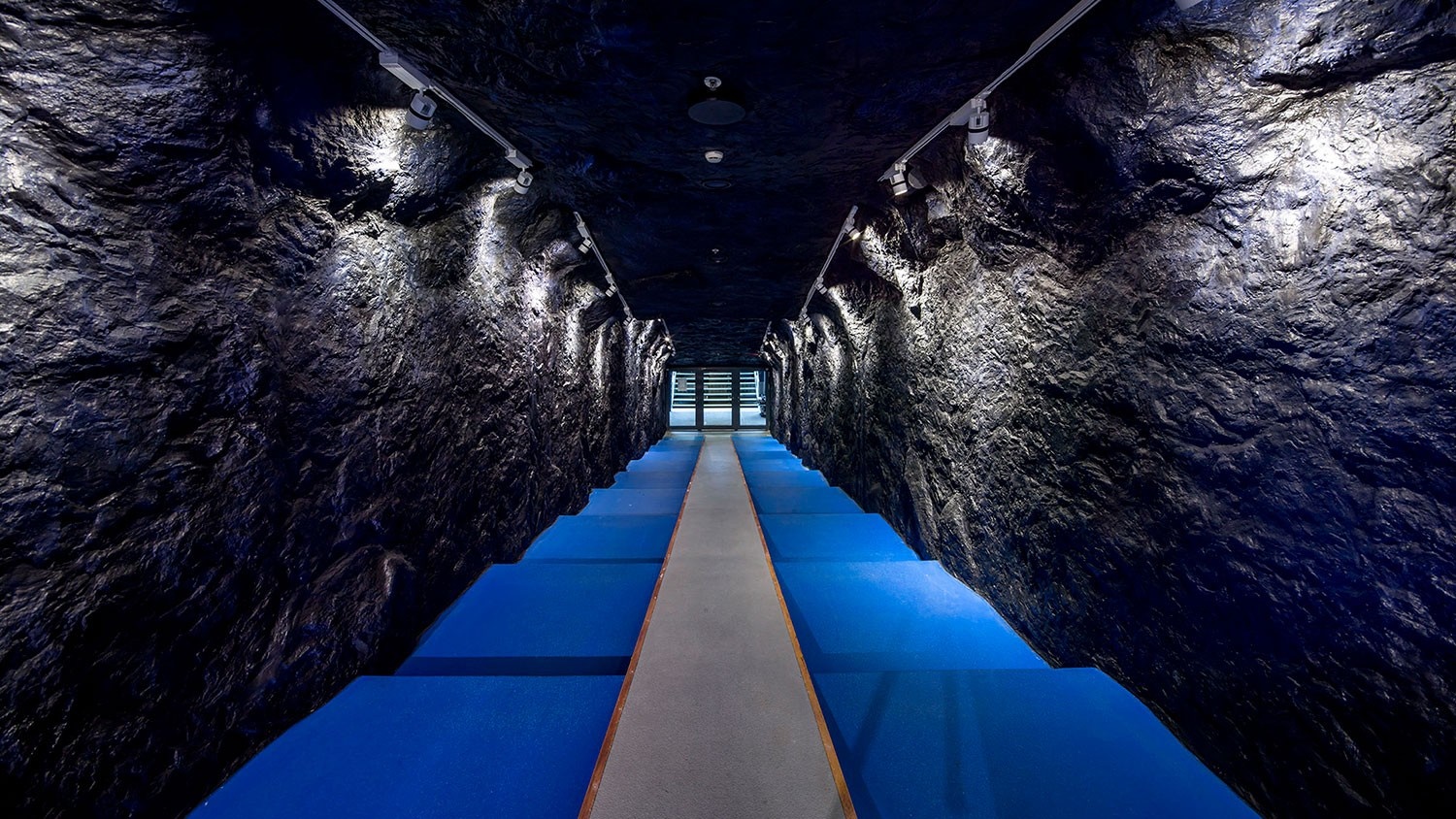 Dark cave-like corridor with blue stairs HD Wallpaper