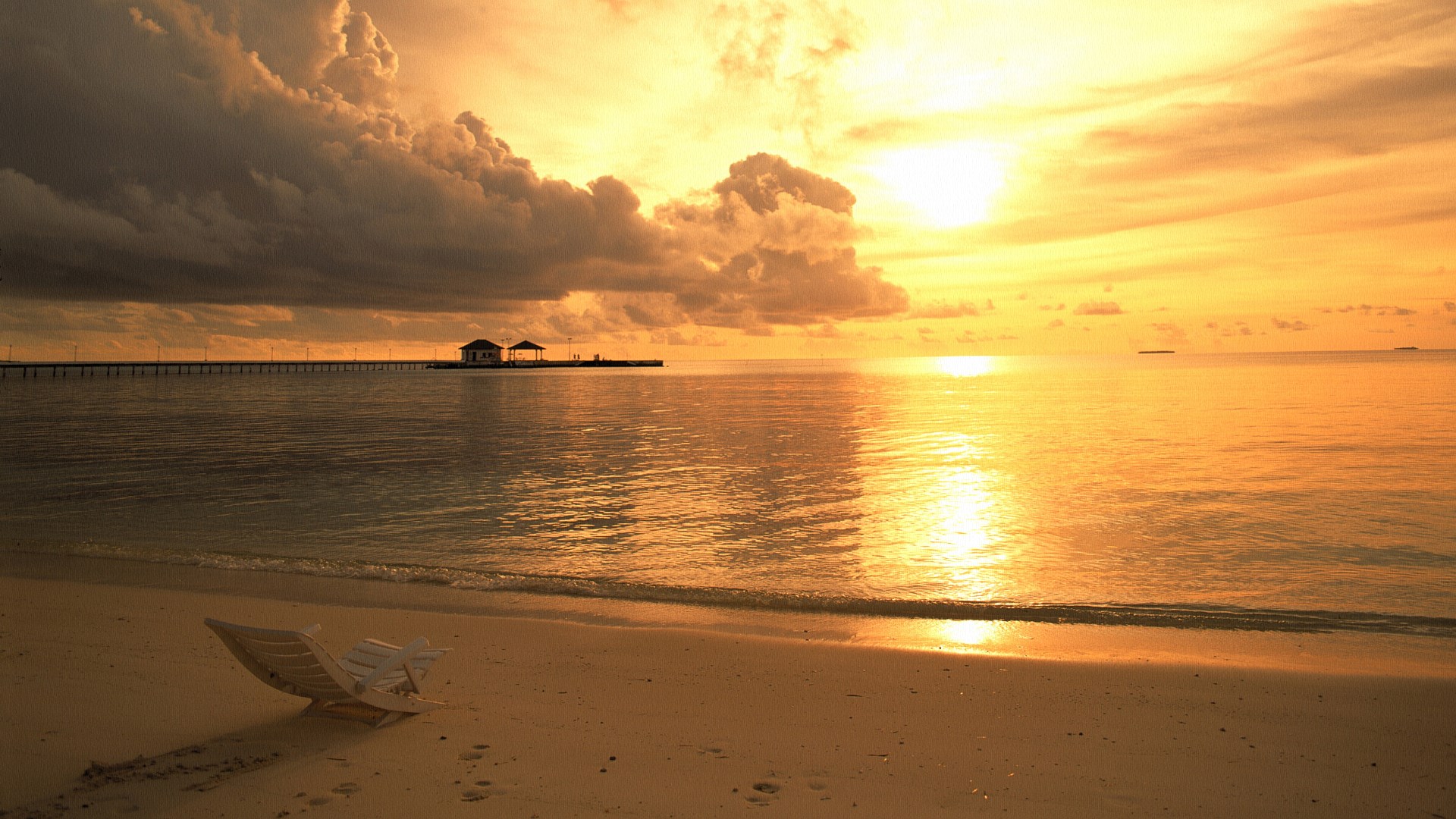 Beach pier at sunset with lounge chair HD Wallpaper