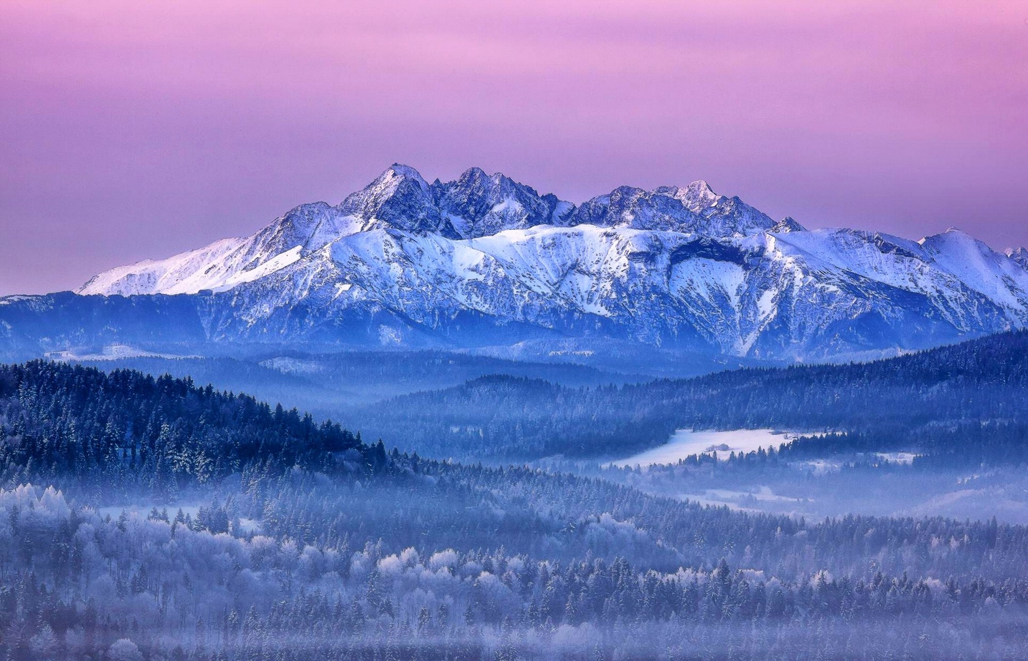 Snow-covered mountains at sunrise with misty forests HD Wallpaper