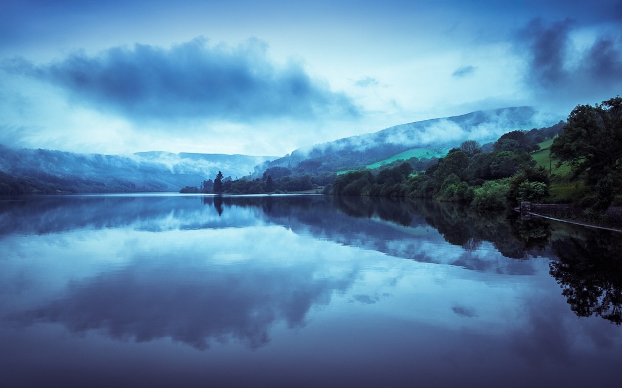 Misty mountains reflected in a calm lake at dawn HD Wallpaper