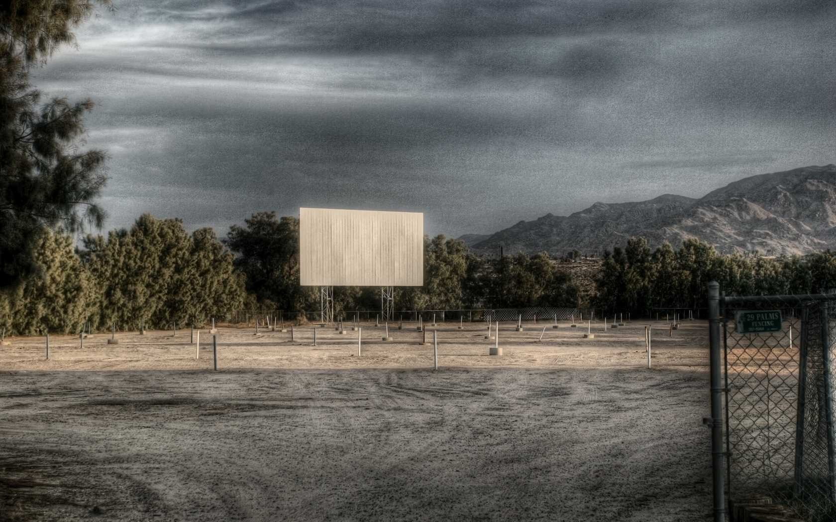 Drive-in movie theater screen with mountains in the background HD Wallpaper