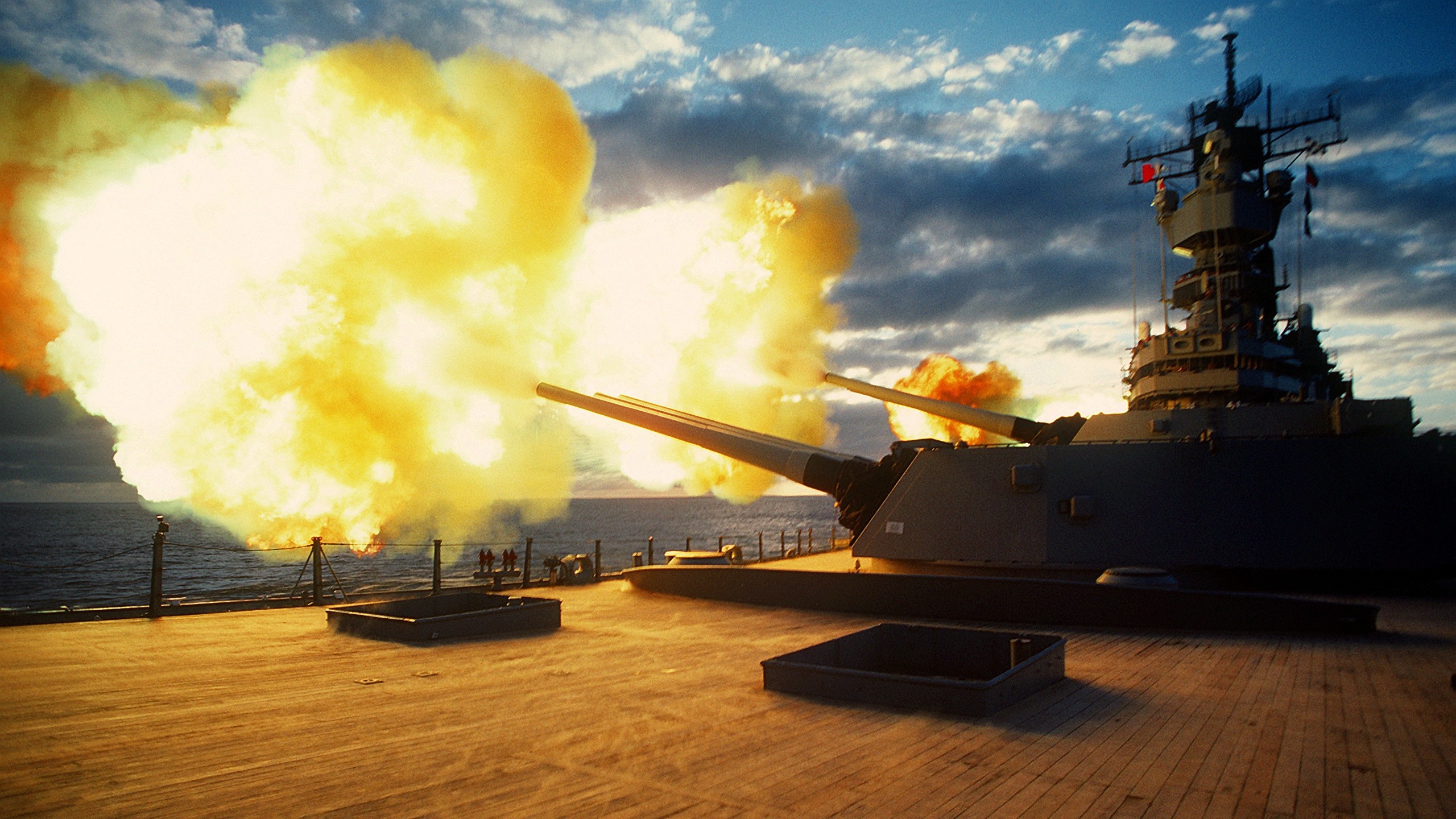 Battleship firing its main guns with large explosions HD Wallpaper