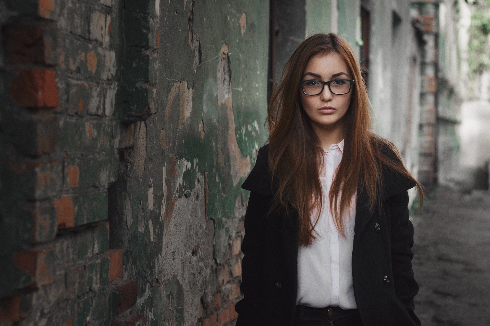Woman with glasses standing in front of a brick wall HD Wallpaper