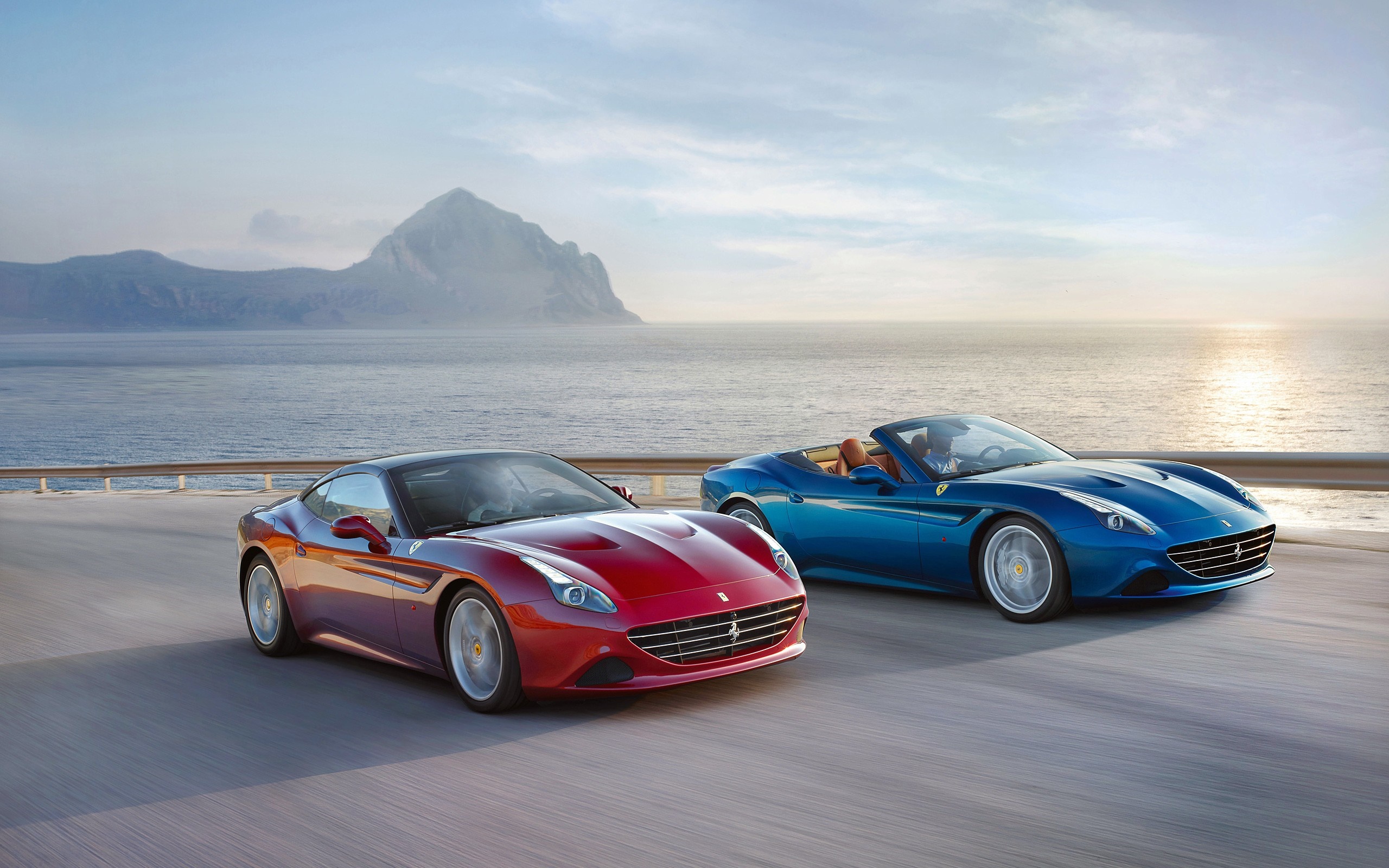 Two Ferrari California T sports cars on a coastal road HD Wallpaper