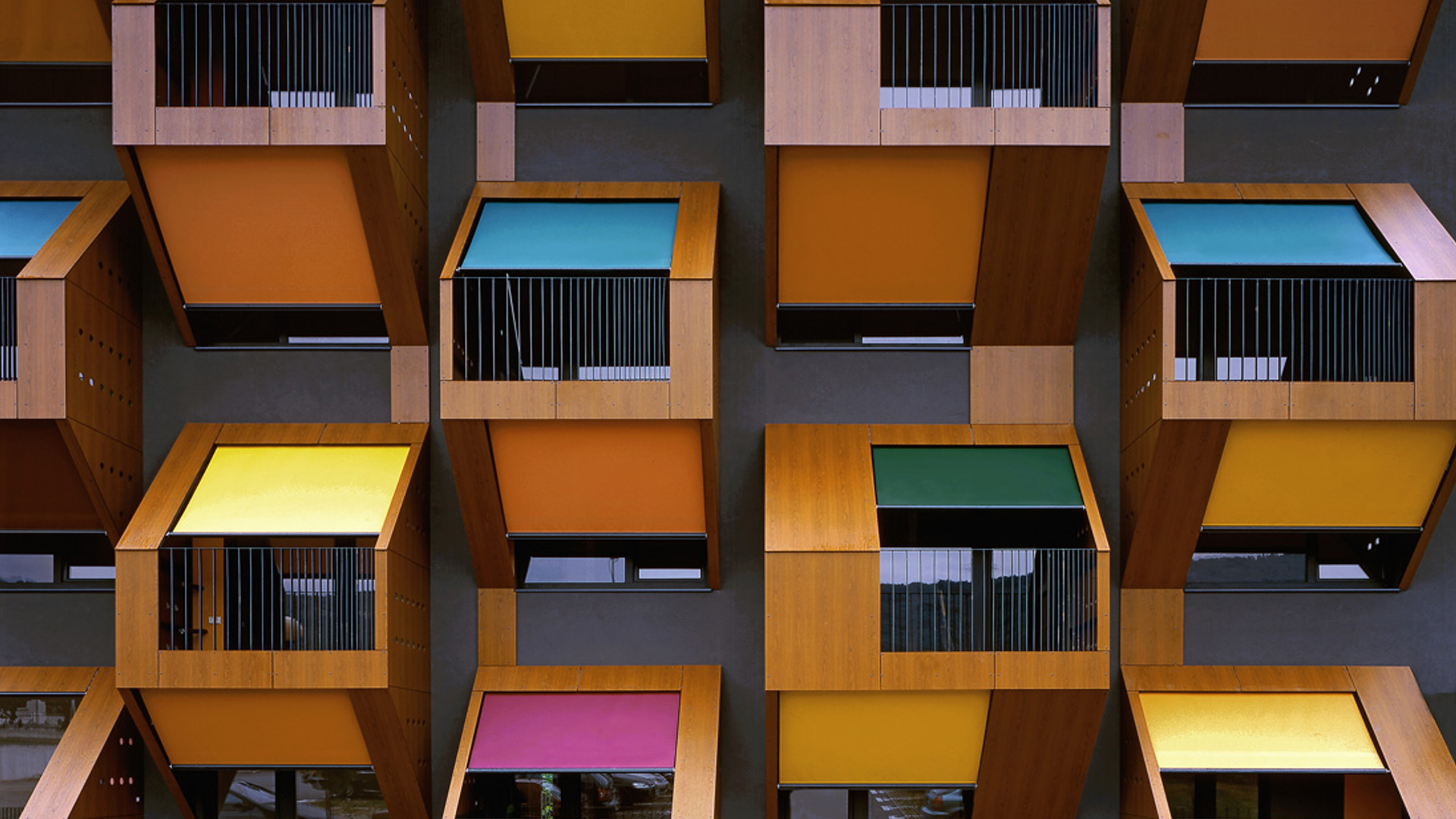 Modern building facade with colorful balconies and awnings HD Wallpaper