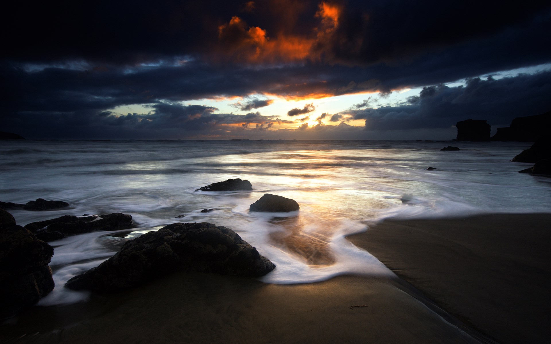 Dark beach with waves and rocks at sunset HD Wallpaper