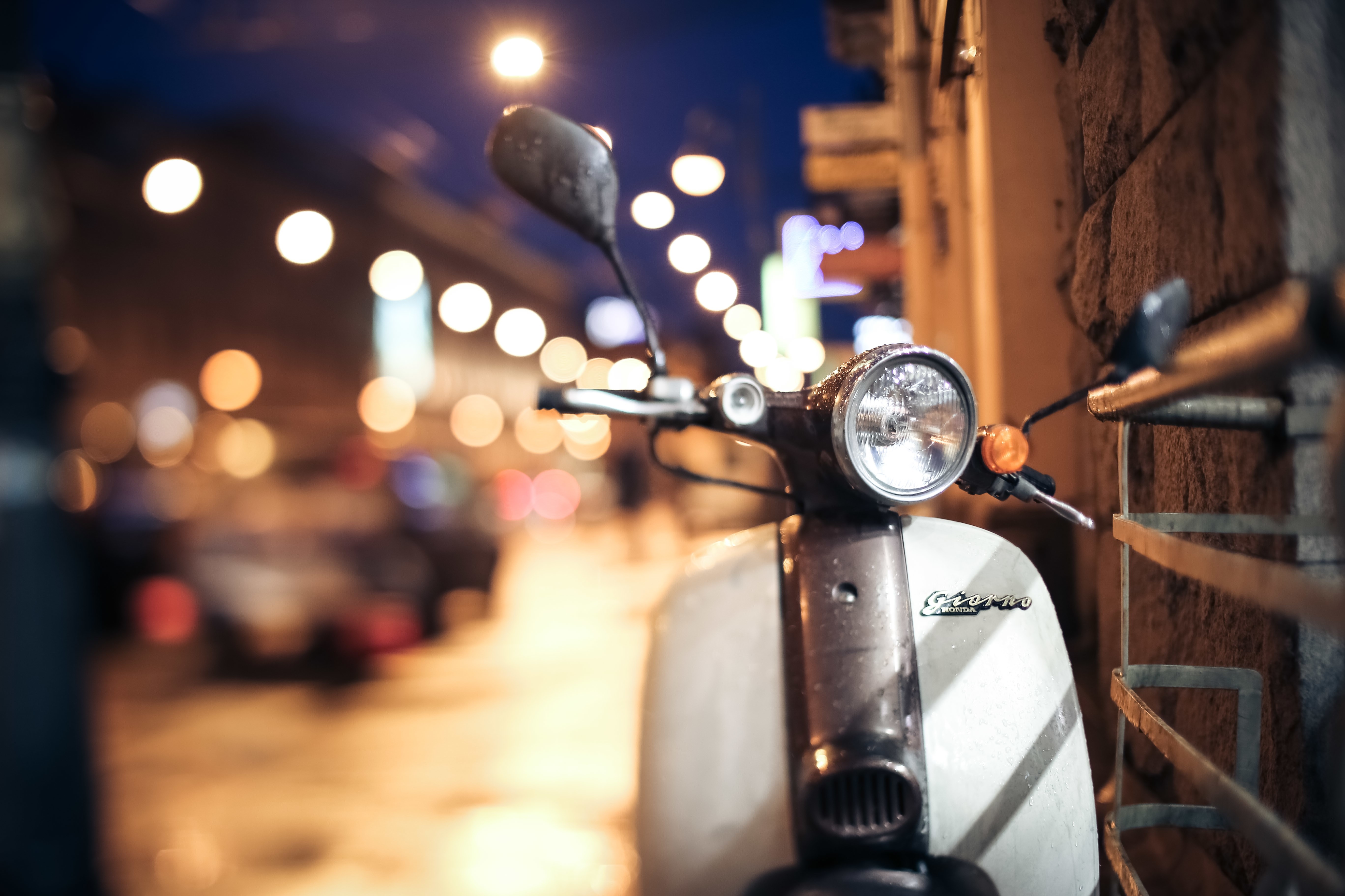 Scooter parked on a city street at night HD Wallpaper