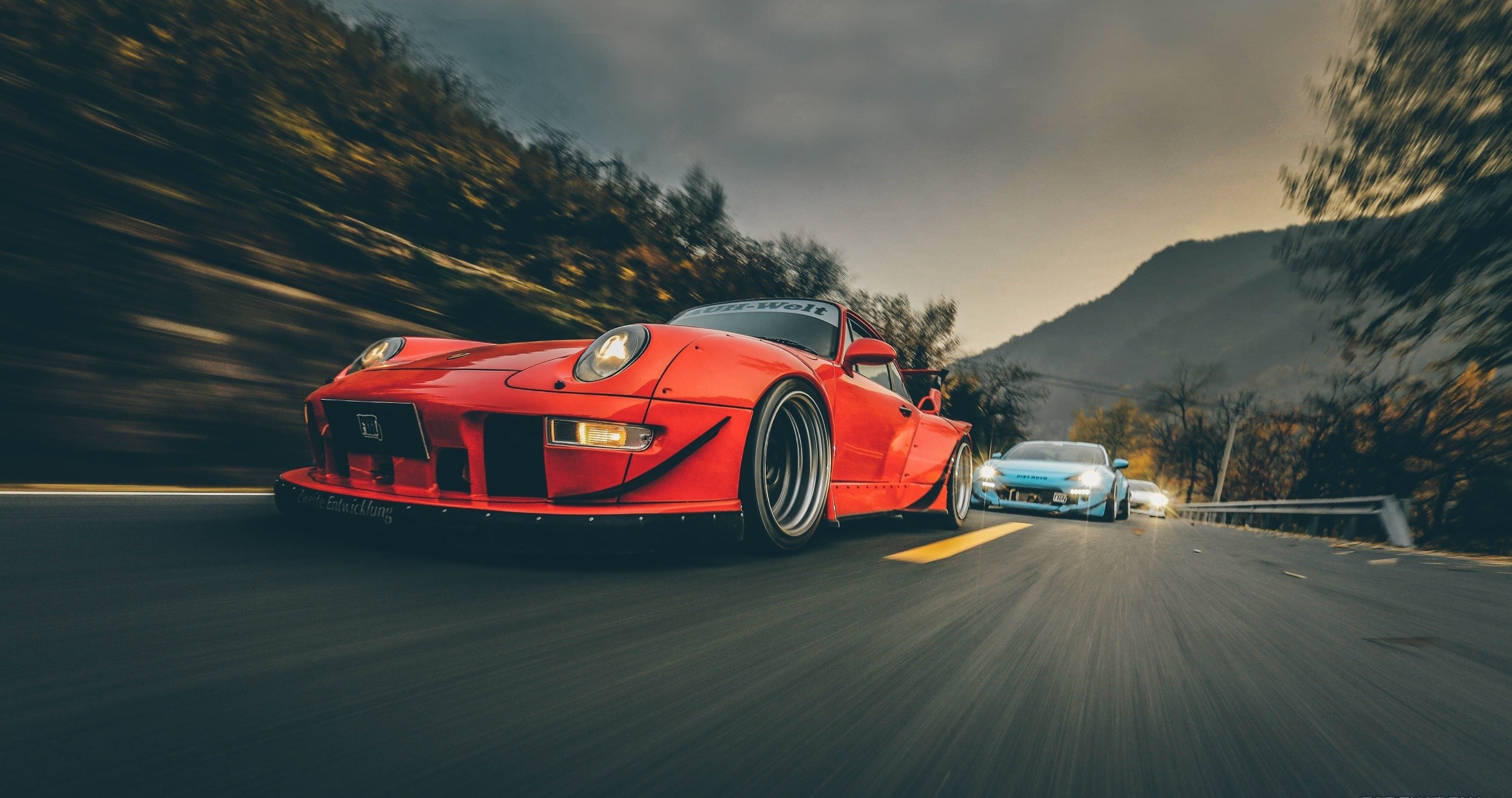 Red Porsche 911 and blue sports car on a road HD Wallpaper