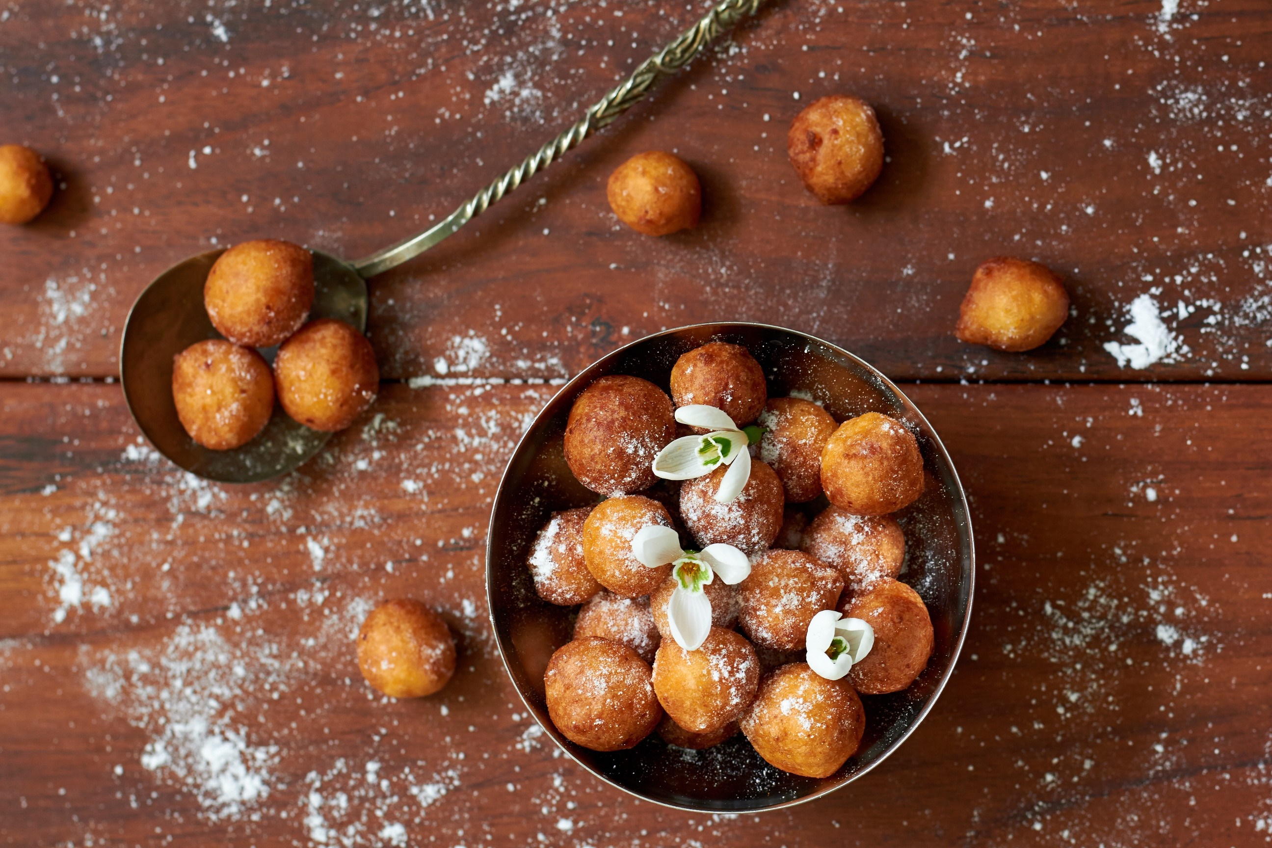 Fried dough balls dusted with powdered sugar and garnished with flowers HD Wallpaper