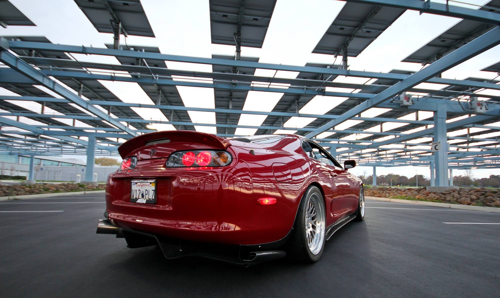 Red Toyota Supra under solar panel canopy HD Wallpaper