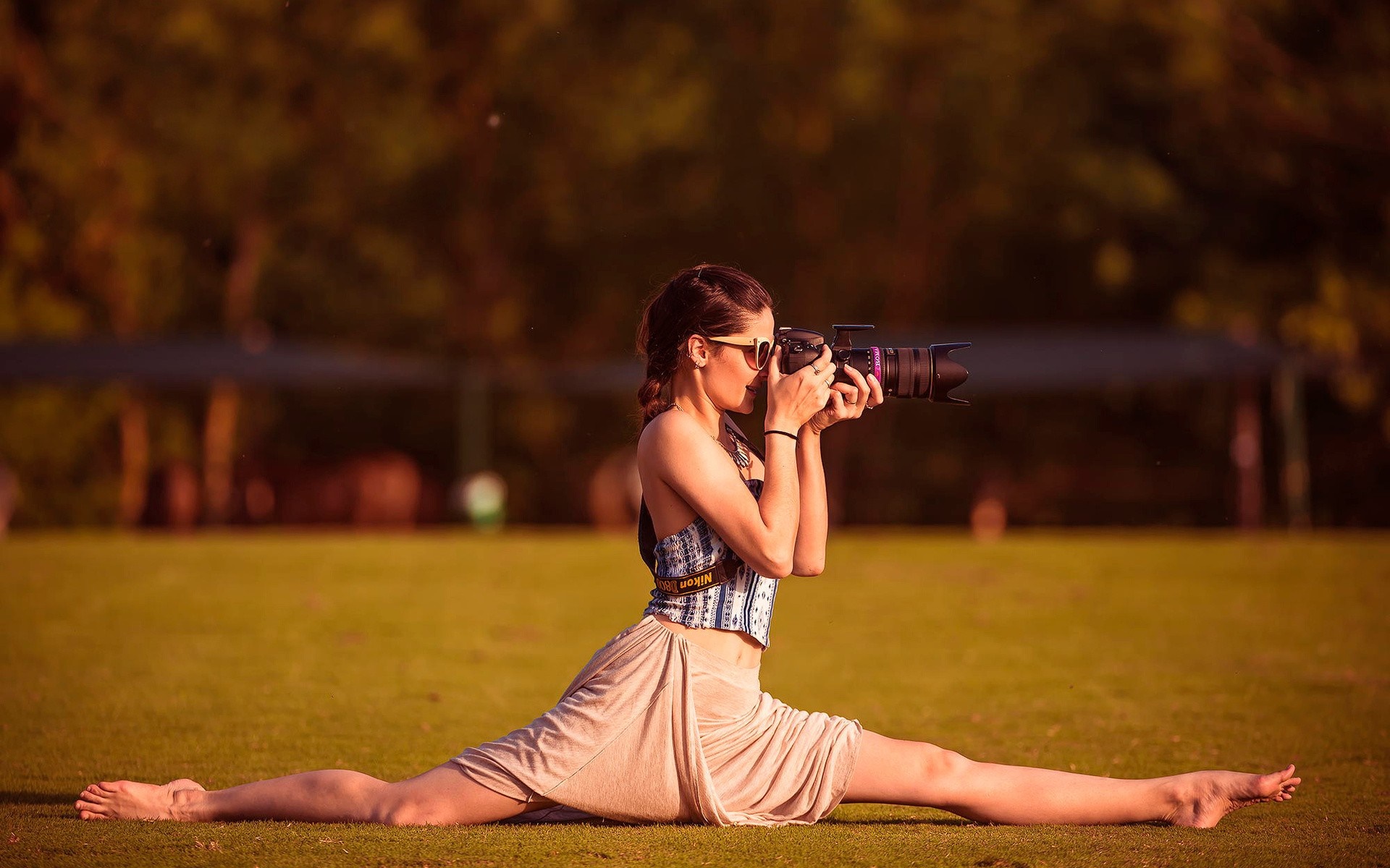Woman in splits taking a photo with a camera HD Wallpaper